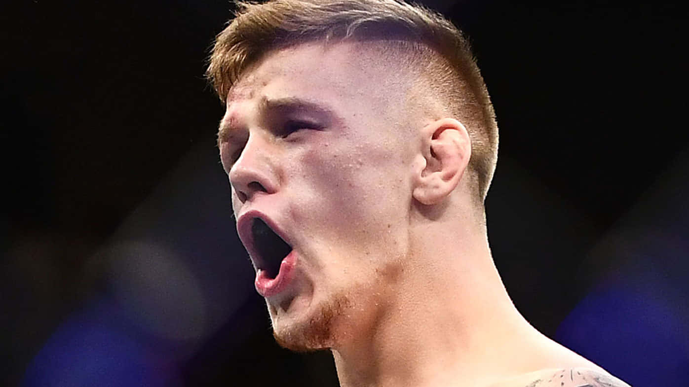 UFC 桌布 壁紙 — 一名戰士在明亮的競技場燈光下，於搏擊運動比賽中專注地大喊的特寫。