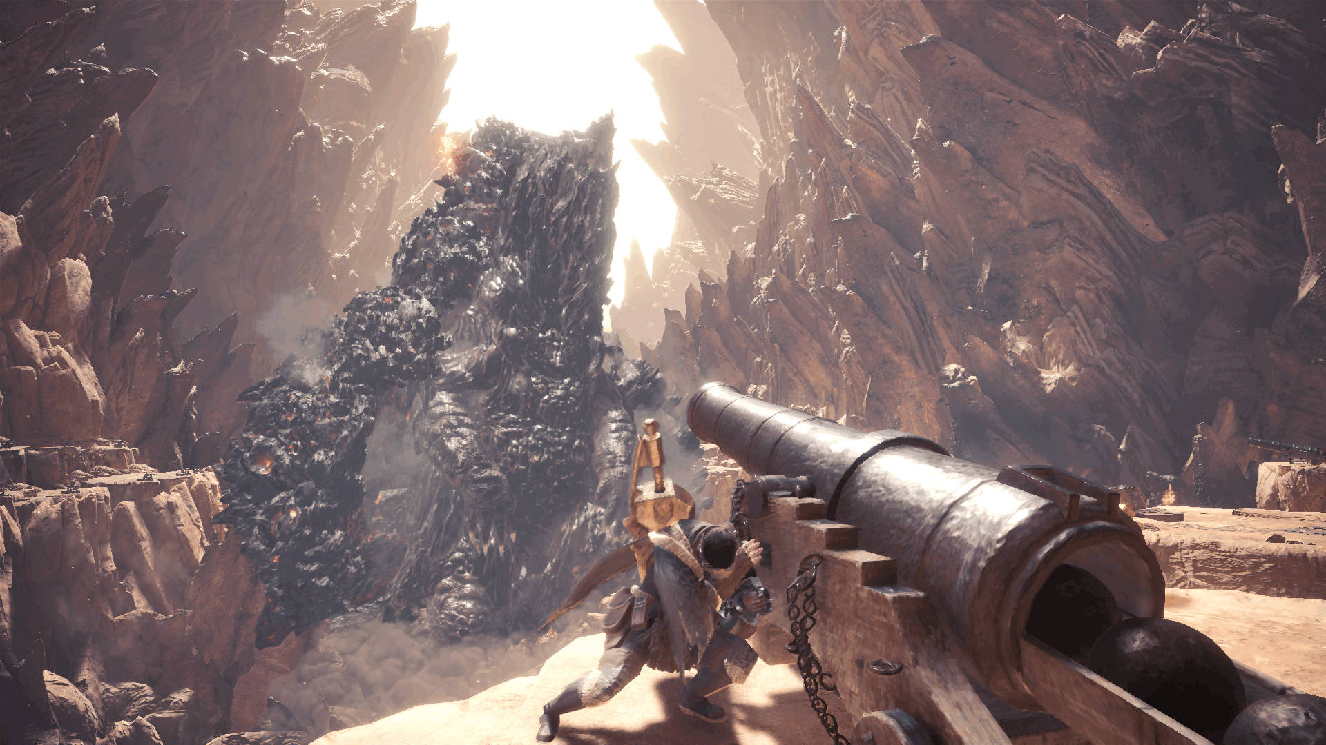 Monster Hunter World Iceborne 桌布 壁紙 — 一名戰士在沙漠峽谷中，在明亮的陽光下向高聳的黑色怪物發射巨大的大砲。