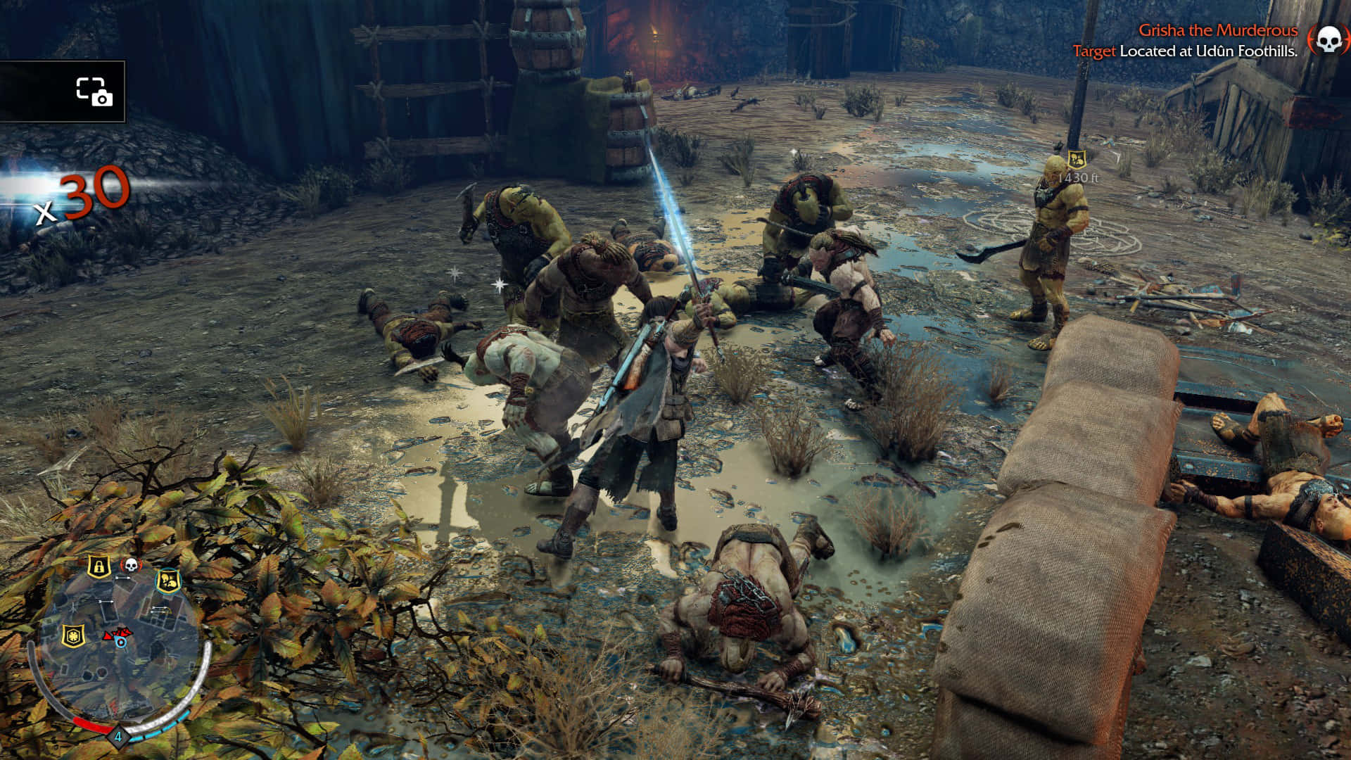 720p Shadow Of Mordor 桌布 壁紙 — 一名戰士在泥濘的戰場上揮舞著發光的劍，周圍是倒下的敵人和木製路障。