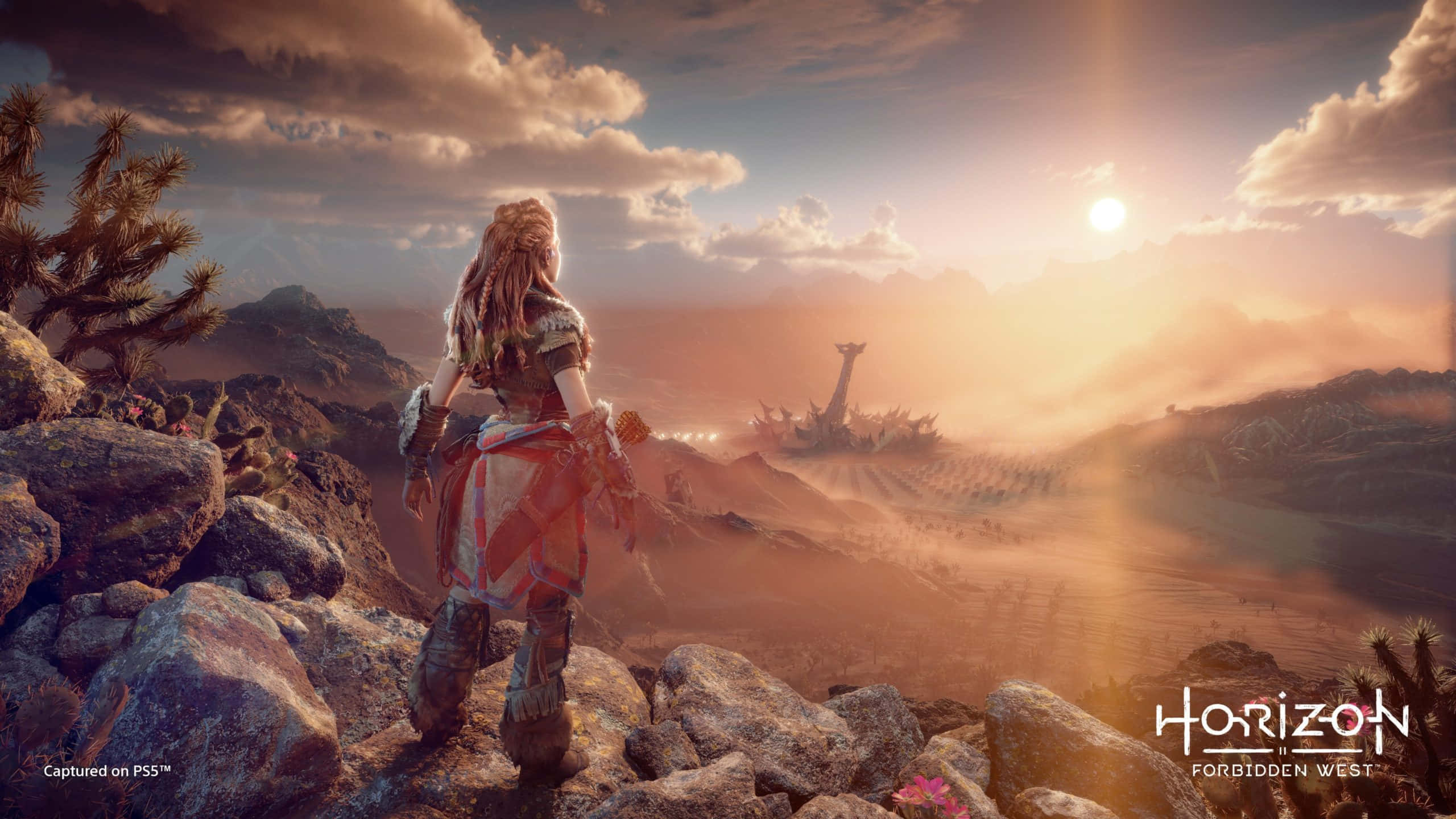 Open-world Games 桌布 壁紙 — 一名戰士站在岩石地形上，凝視著金色夕陽天空下的遙遠機械廢墟。