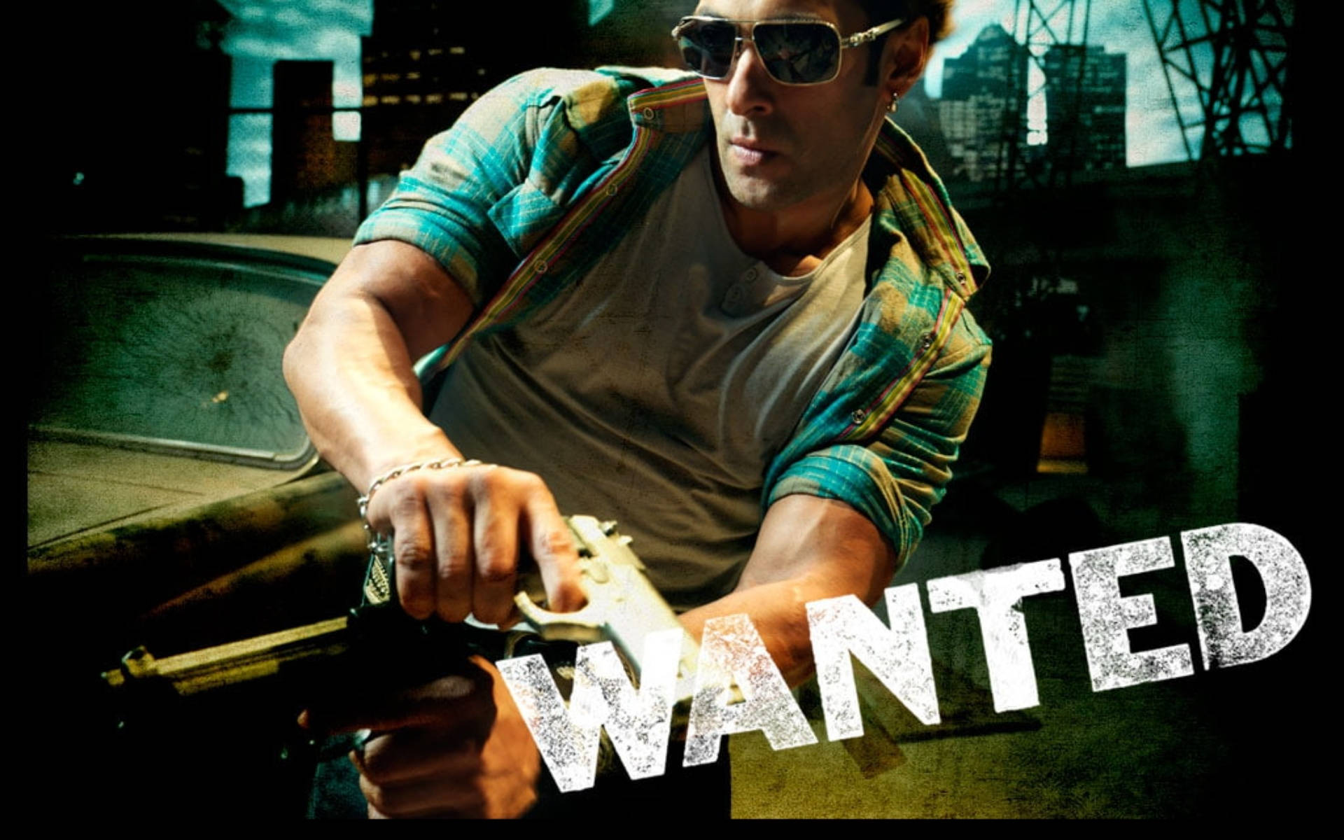 Salman Khan 桌布 壁紙 — 一名戴太陽眼鏡的男子在粗糙的城市背景下，用帶有「WANTED」海報疊加效果的槍瞄準。