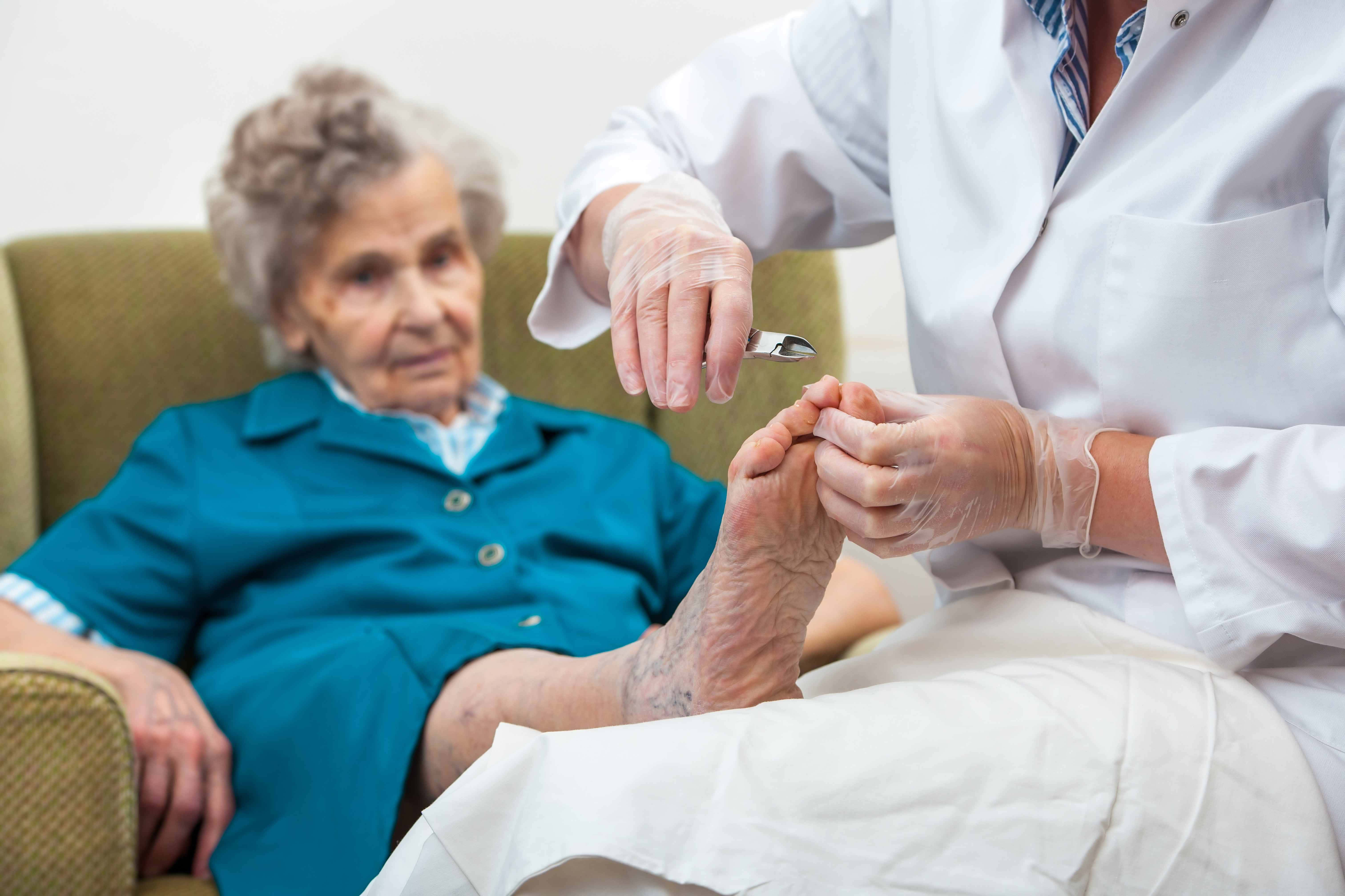 Foot 桌布 壁紙 — 一名戴手套的醫護人員正在為一位安坐於椅子上的老婦修剪腳趾甲。
