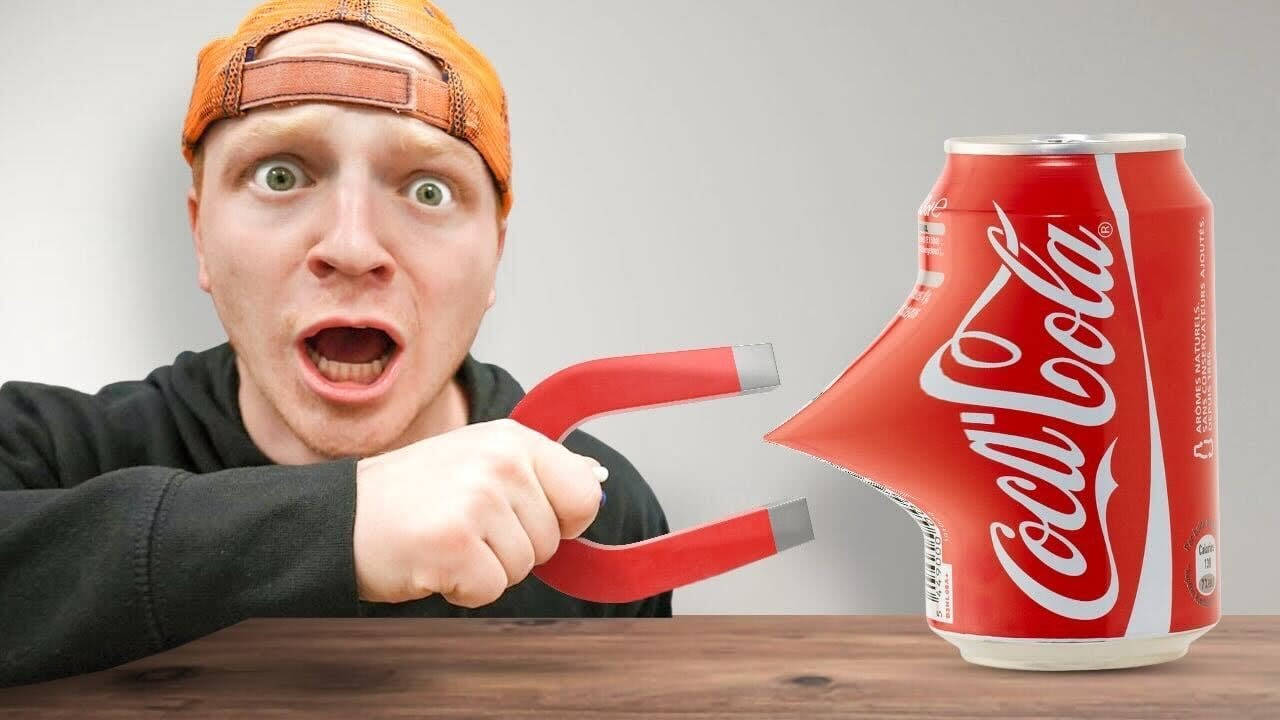 Drink 桌布 壁紙 — 一名戴橙色帽子的男子用紅色磁力鉗將可口可樂罐拉向自己，表情震驚。