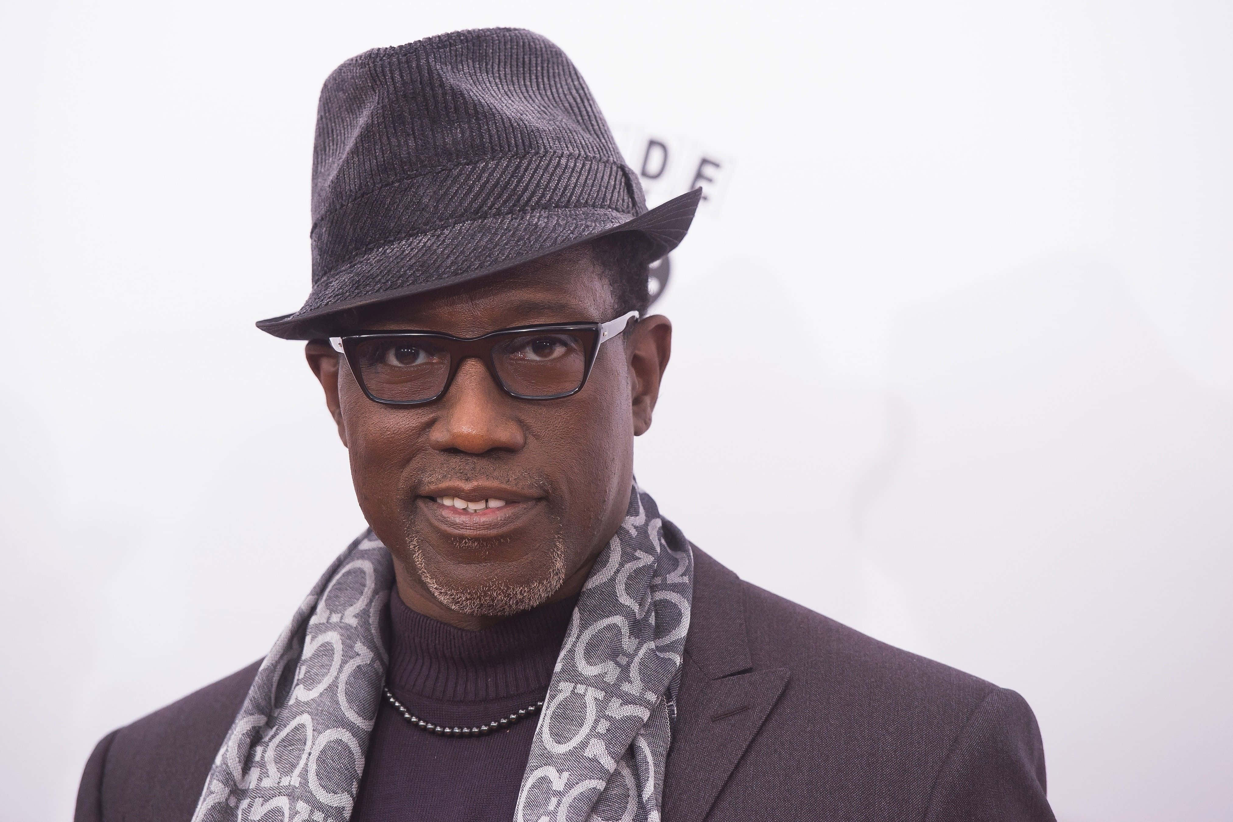 Wesley Snipes 桌布 壁紙 — 一名戴灰色紳士帽、眼鏡及圖案圍巾的男子在純白背景前對著鏡頭微笑。