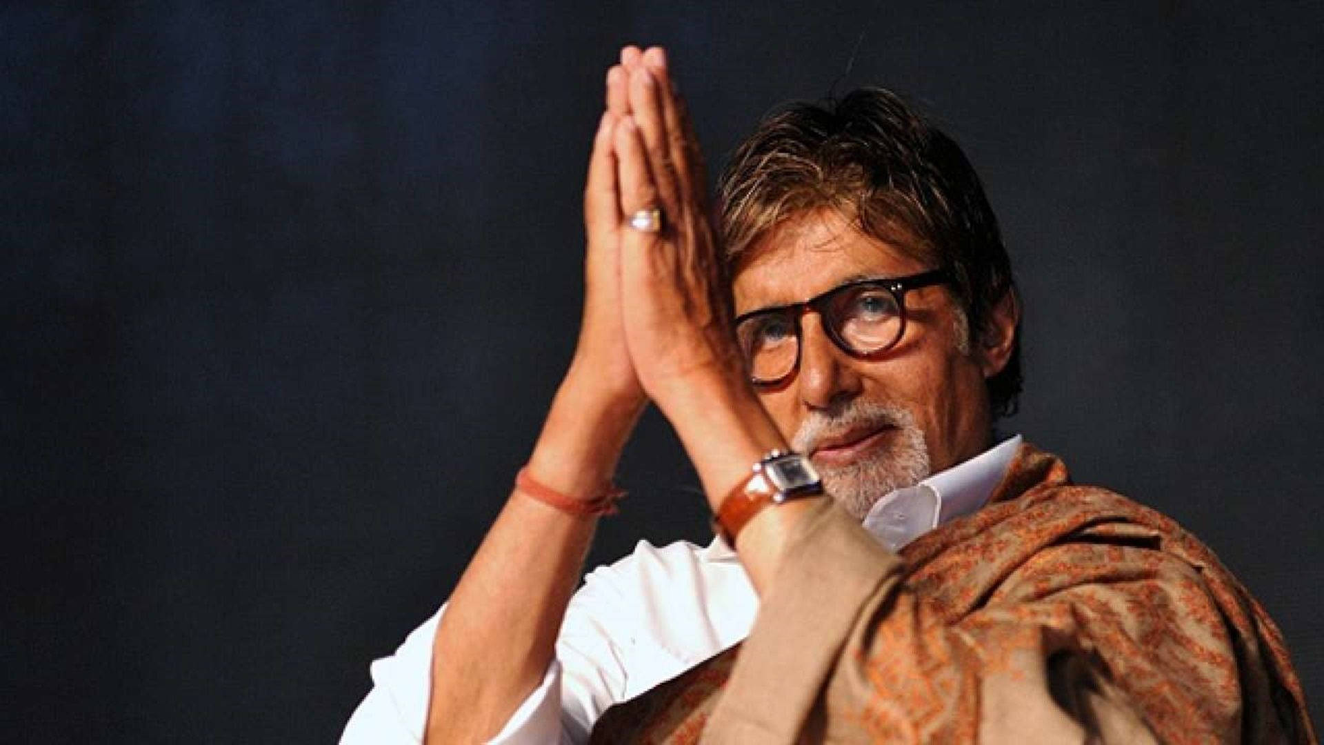 Amitabh Bachchan 桌布 壁紙 — 一名戴眼鏡、披著圖案披肩的男子，在深色背景下以恭敬的姿態合十雙手。
