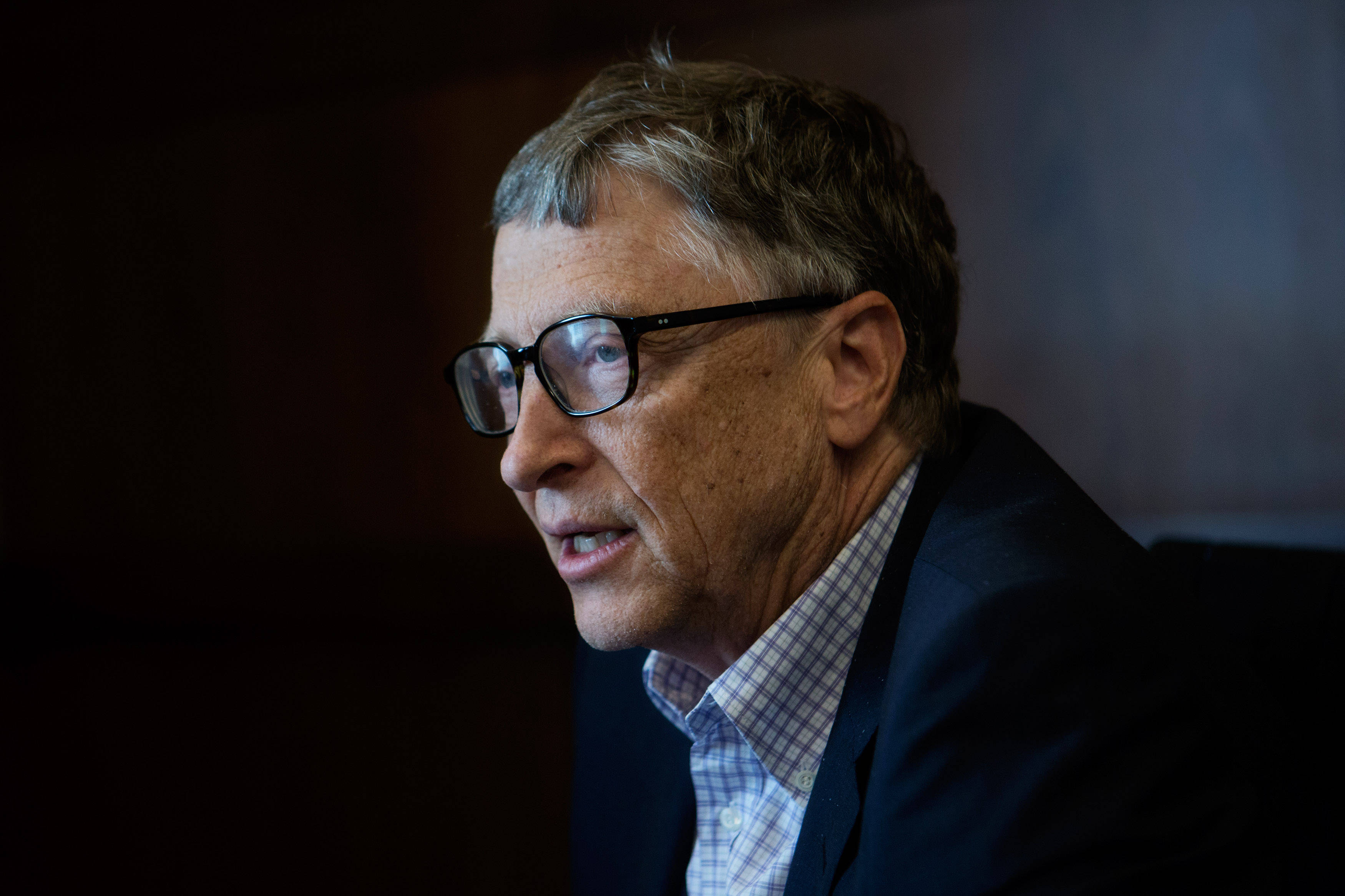 gates 桌布 壁紙 — 一名戴眼鏡、灰白頭髮、身穿深色西裝的男子，在模糊背景下的特寫肖像。