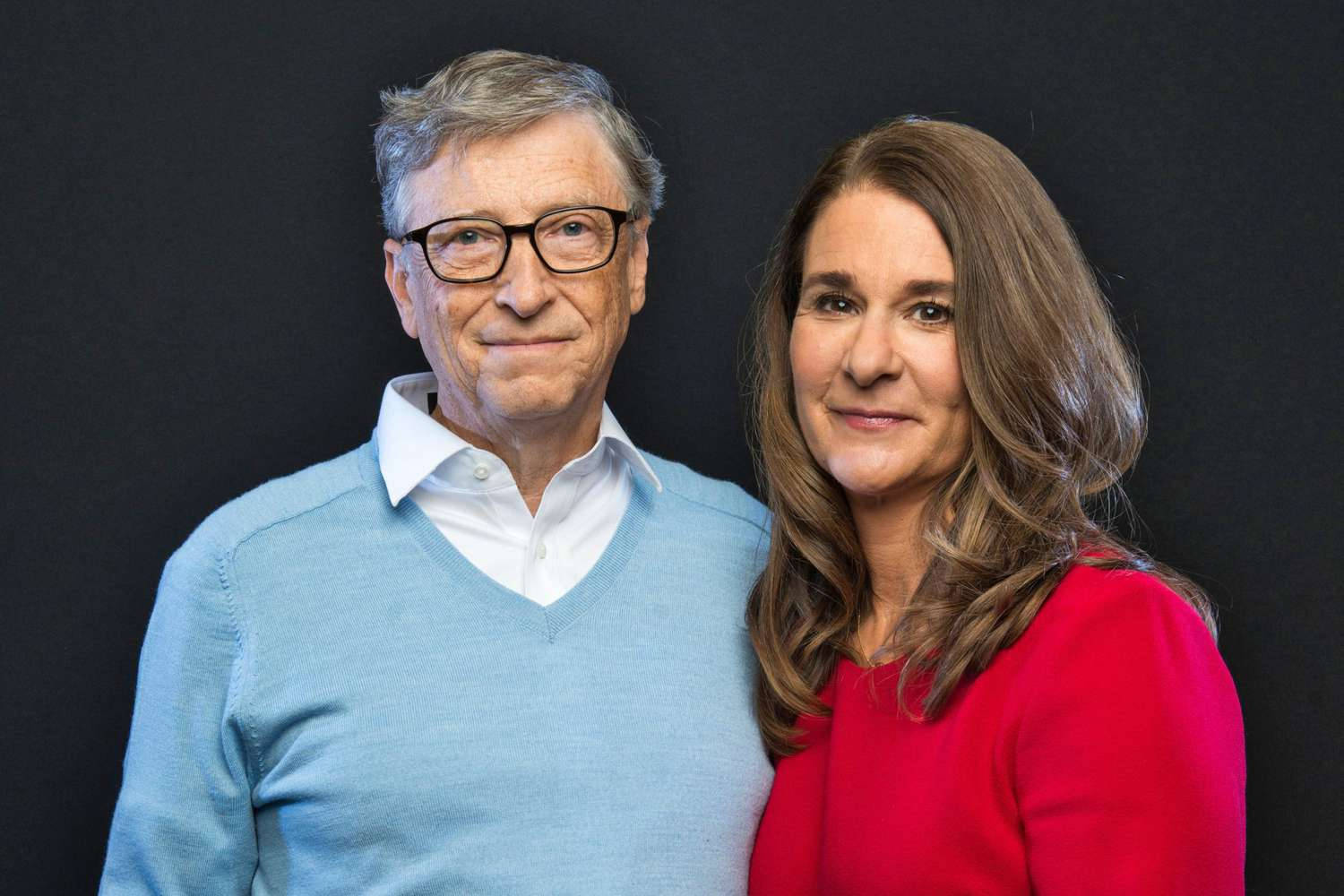 戴眼鏡的男子與紅衣女子在工作室肖像中並肩而立。 — Microsoft 壁紙