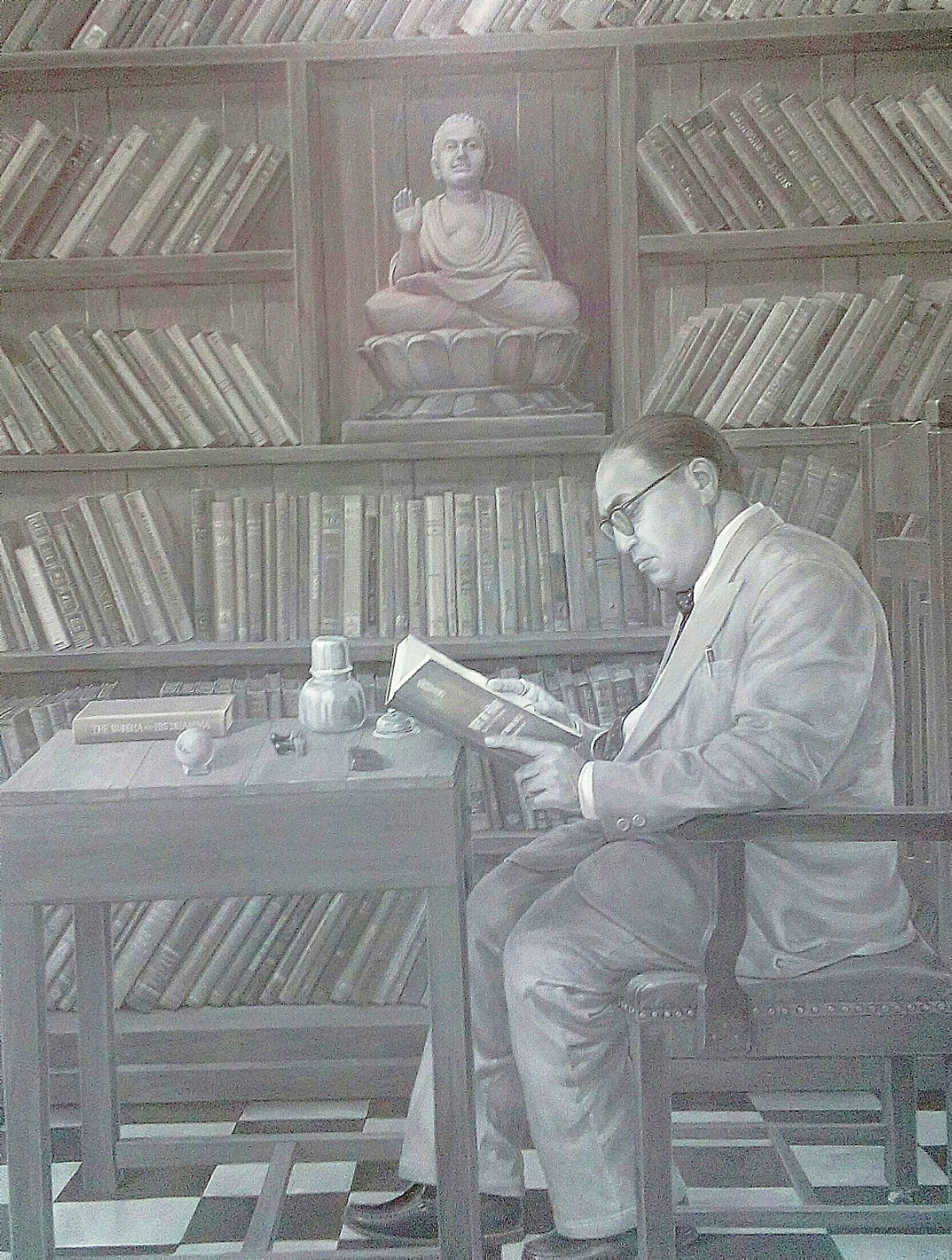 Ambedkar 桌布 壁紙 — 一名戴眼鏡的男子在書桌前看書，周圍是高聳的書架和一尊佛像。
