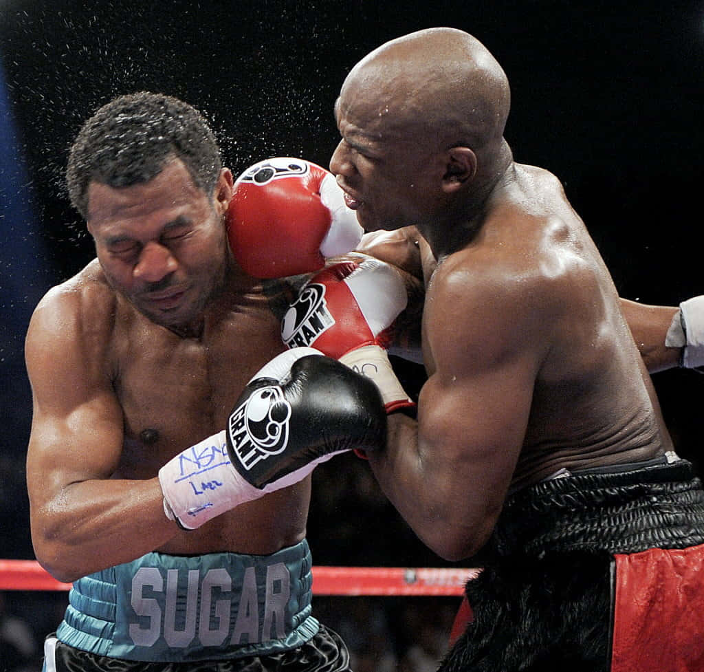 Boxing 桌布 壁紙 — 一名戴紅色拳擊手套的拳擊手在擂台上揮出重拳擊中對手面部，汗水飛濺。