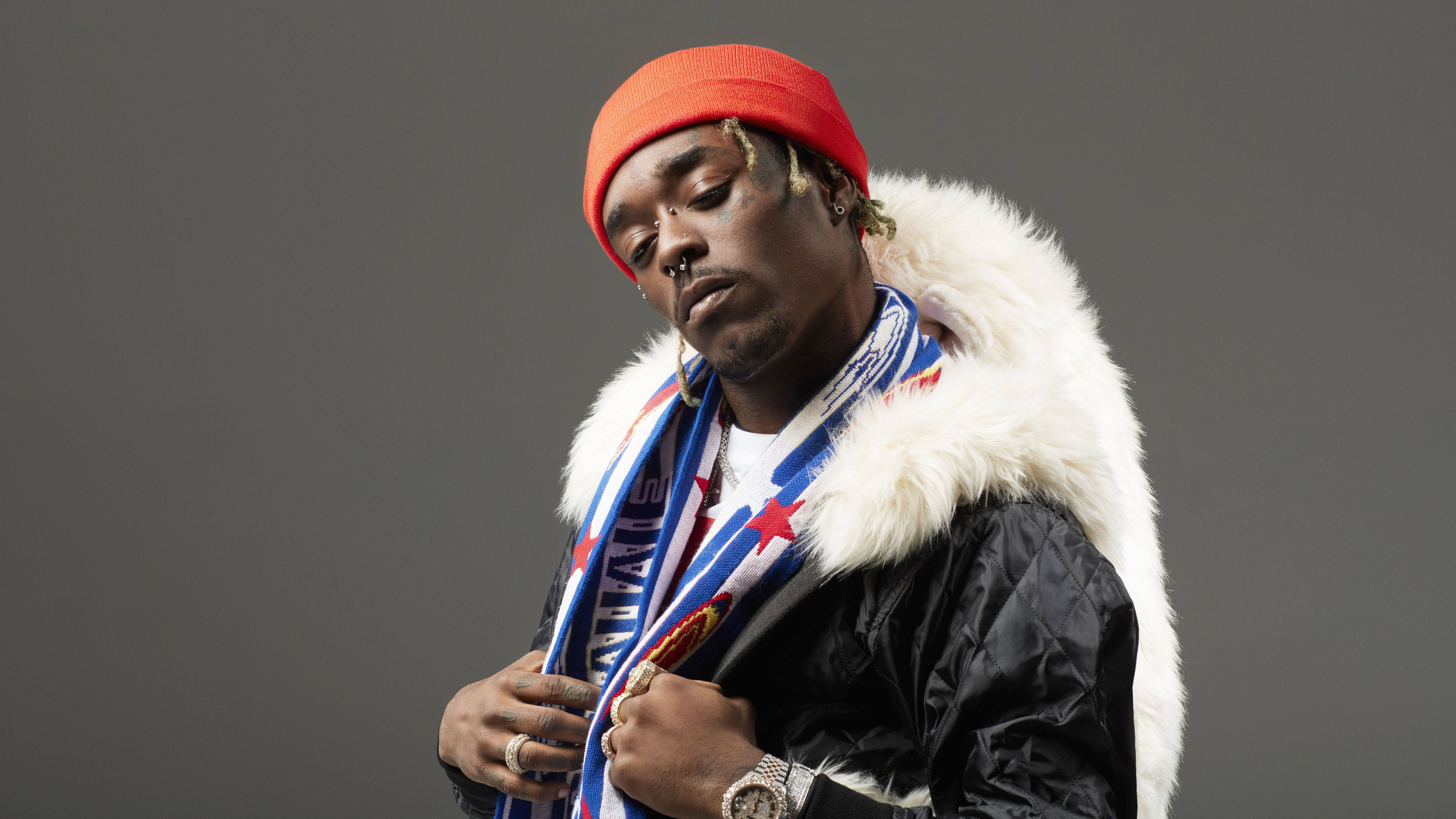 Lil Uzi Desktop 桌布 壁紙 — 一名戴紅色毛帽、穿毛領外套的男子，在灰色攝影棚背景前閉眼擺姿勢。