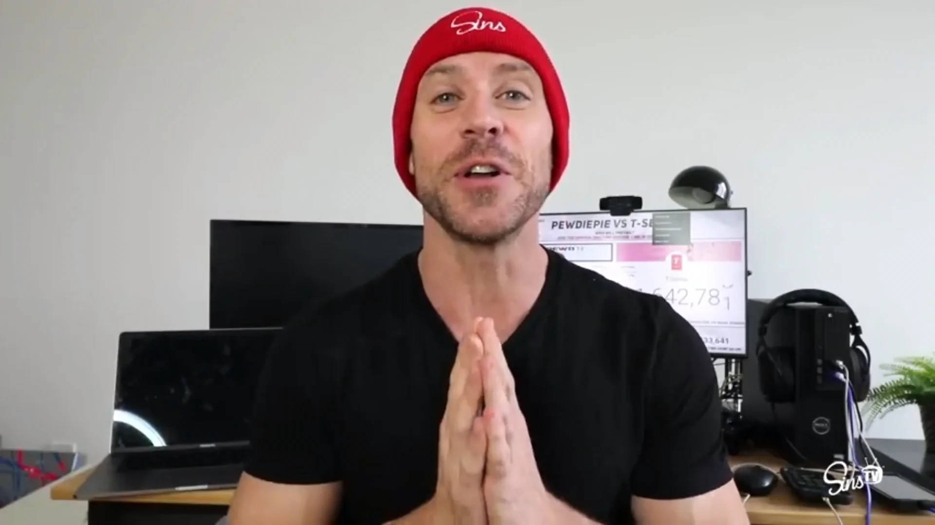 Celebrity 桌布 壁紙 — 一名戴紅色毛帽、穿黑色襯衫的男子，在顯示PewDiePie對T-Series YouTube圖表的顯示器前合十雙手。