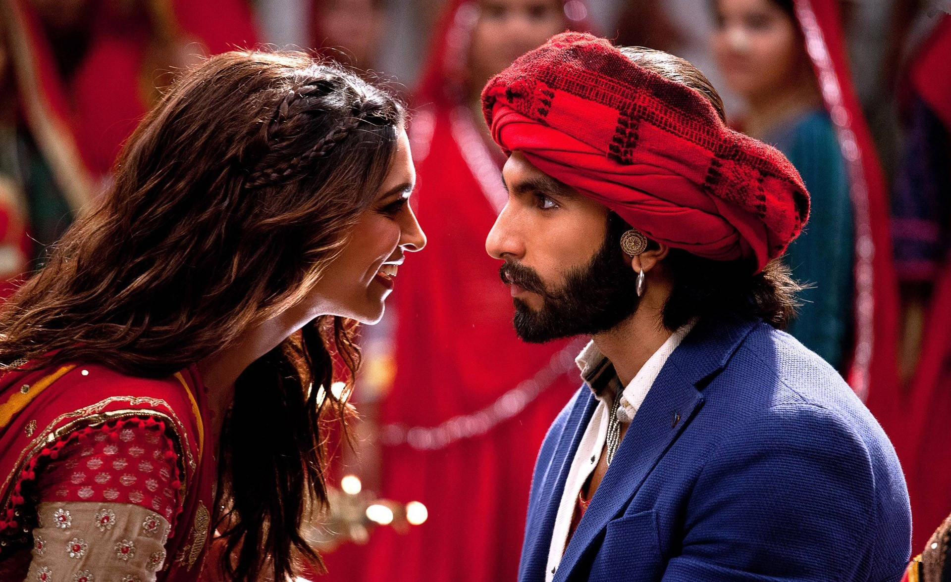 Ranveer Singh 桌布 壁紙 — 一名戴紅色頭巾、穿藍色西裝的男子溫柔地凝視著一名身穿紅色刺繡服裝的女子，他們正共享親密時刻。