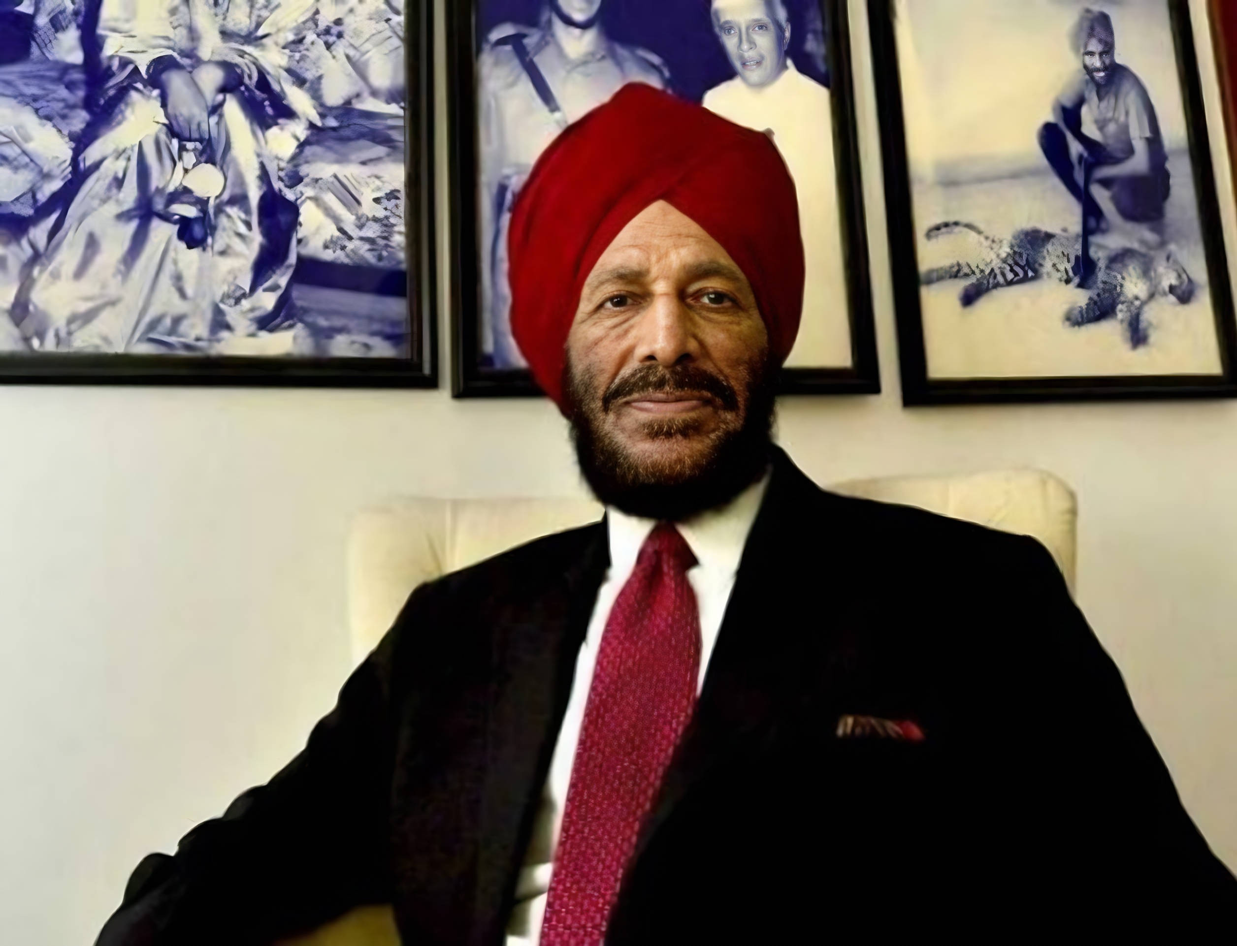 Milkha Singh 桌布 壁紙 — 一名戴紅色頭巾、身穿西裝的男子自信地坐在椅子上，身後有裱框的黑白照片。