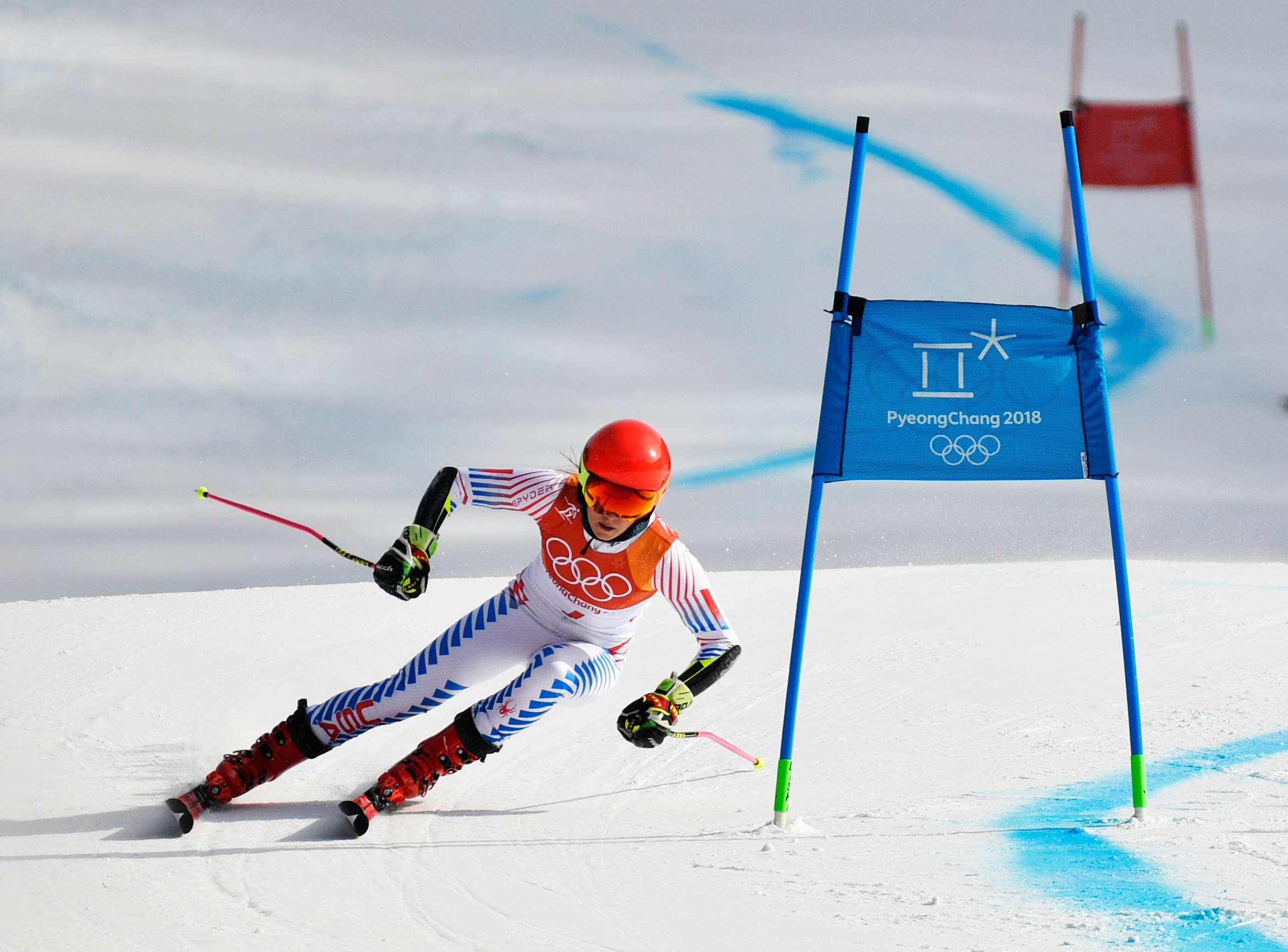 Winter Olympics 桌布 壁紙 — 一名戴紅色頭盔、身穿白色滑雪服的滑雪運動員在平昌2018冬奧會上，在藍色旗門之間穿過雪地。