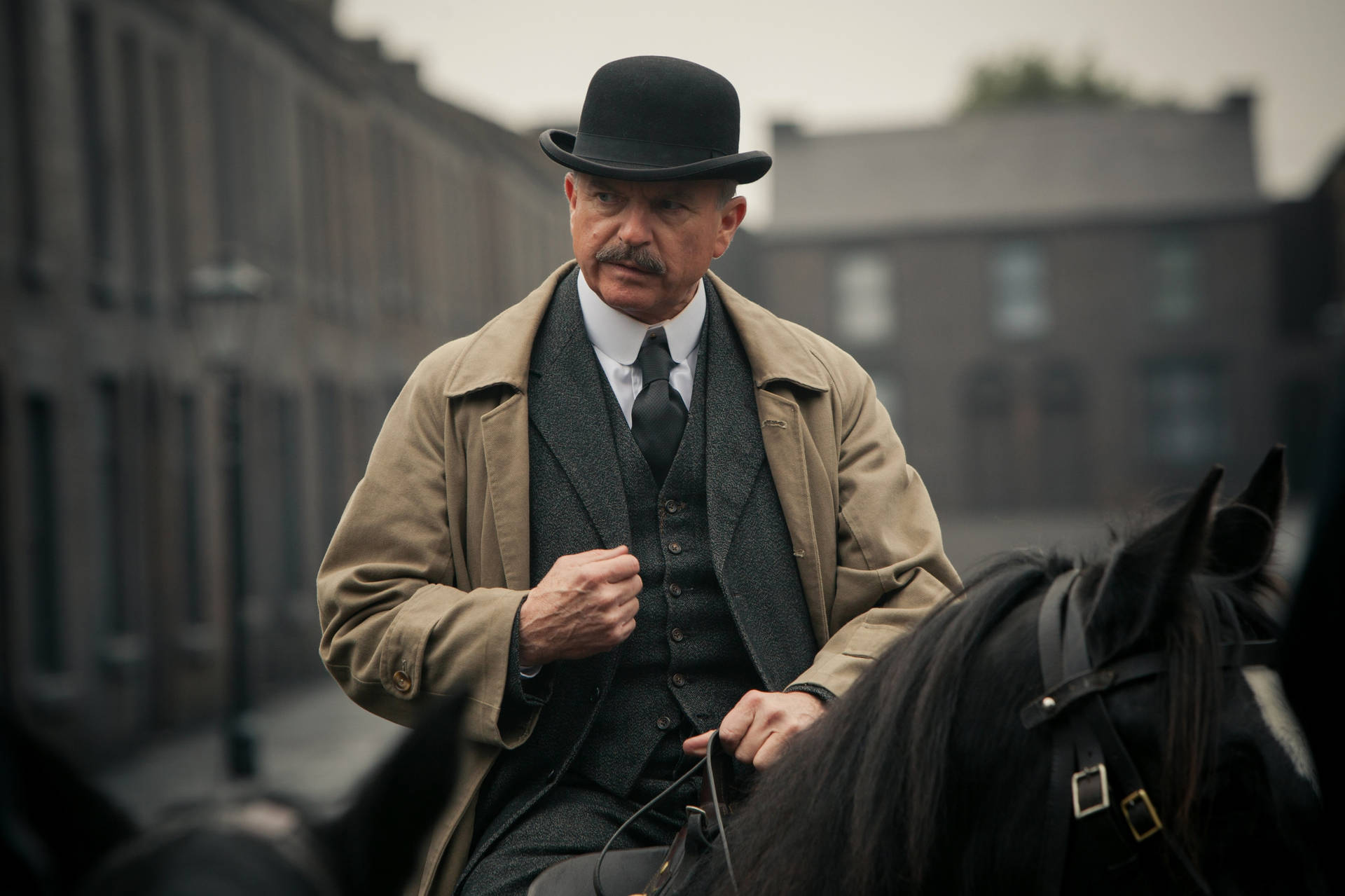 穿著復古服裝的男子騎馬穿過霧氣瀰漫的城市街道。 — Peaky Blinders 壁紙