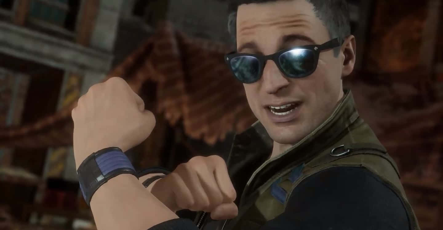 Johnny Cage 桌布 壁紙 — 一名戴著太陽眼鏡和戰術背心的男子，在粗糙的城市環境中自信地微笑並彎曲手臂。