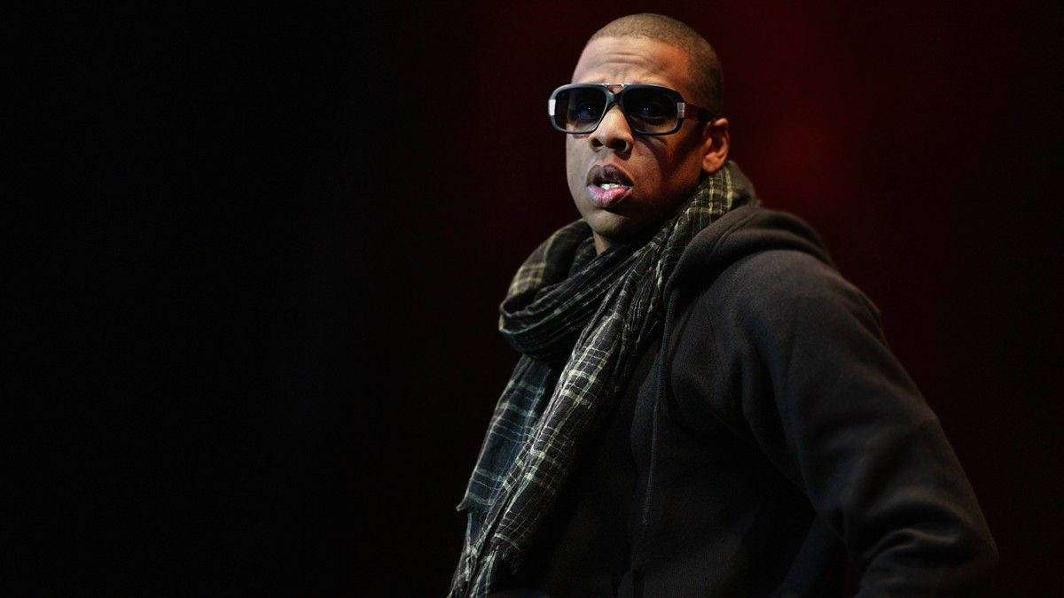 Jay-z 桌布 壁紙 — 一名戴著太陽眼鏡和格子圍巾的男子站在深紅色背景前，燈光效果戲劇化。