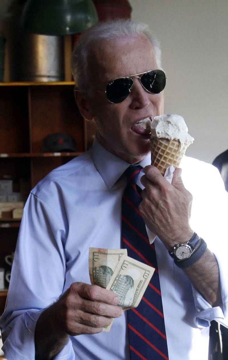 Biden 桌布 壁紙 — 一名戴著太陽眼鏡和領帶的男子在溫暖燈光的室內環境中，一邊吃香草冰淇淋，一邊手持現金。