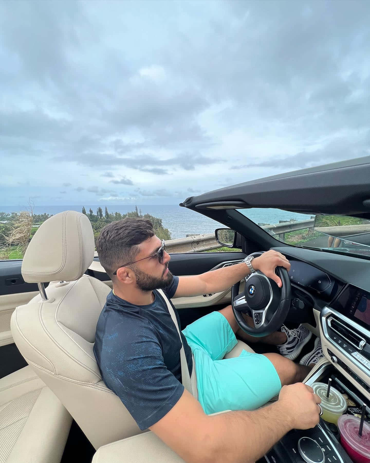 driving 桌布 壁紙 — 一名戴著太陽眼鏡的男子在陰天駕駛敞篷車沿著海岸公路行駛，可欣賞海景。