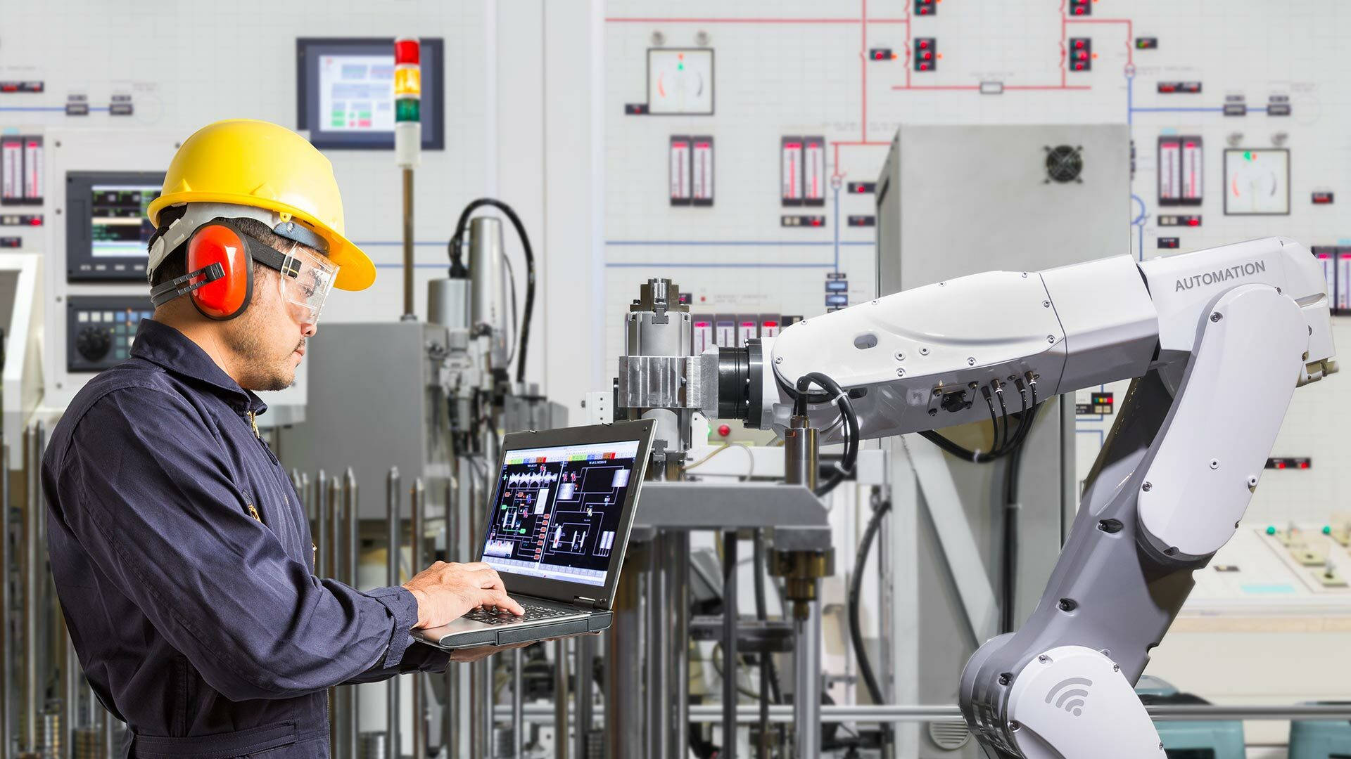 engineering 桌布 壁紙 — 一名戴著安全帽和耳罩的技術人員正在高科技工廠控制室監控機械臂。