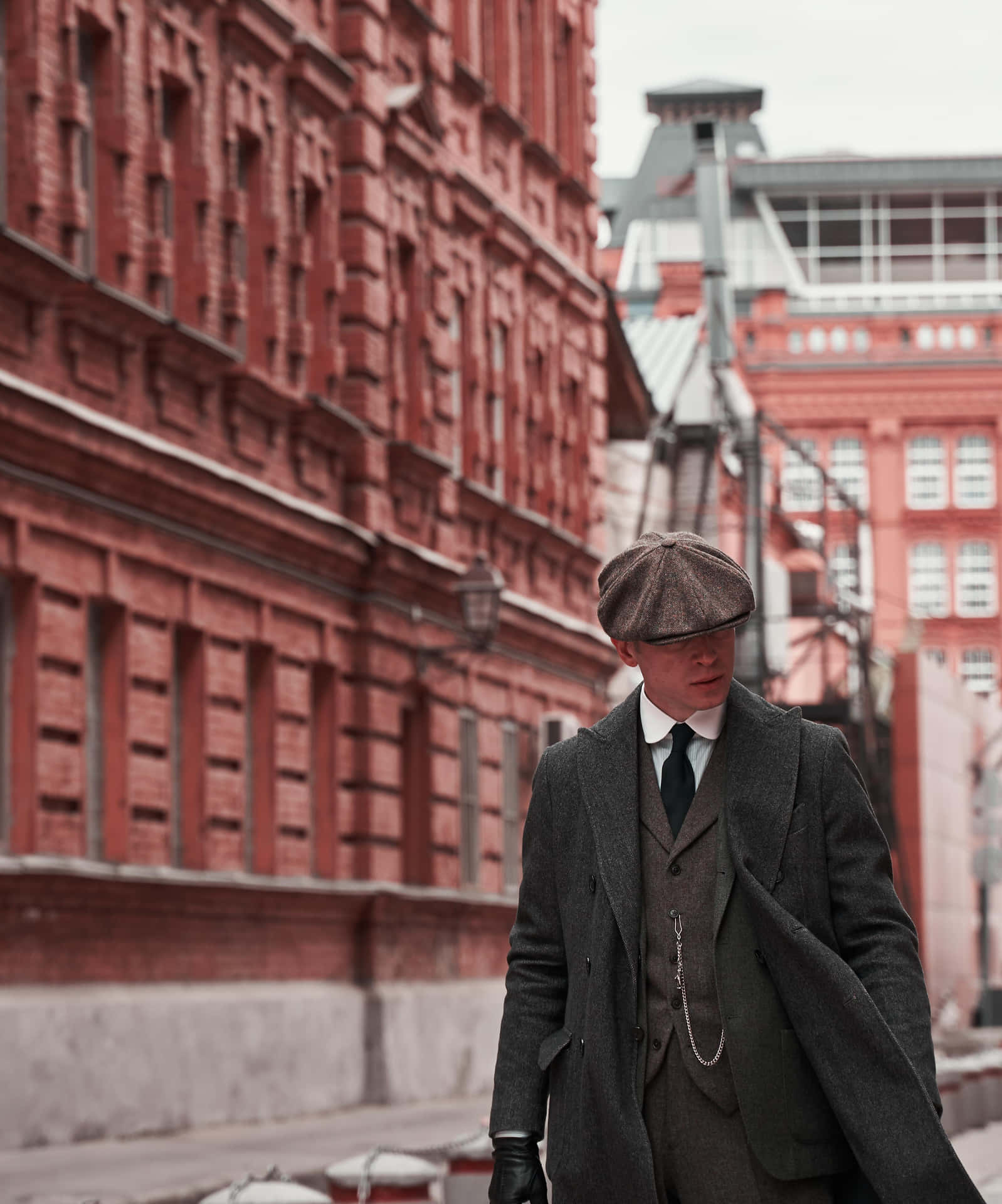 穿著復古大衣和帽子的男子在磚街上行走 — Peaky Blinders 壁紙