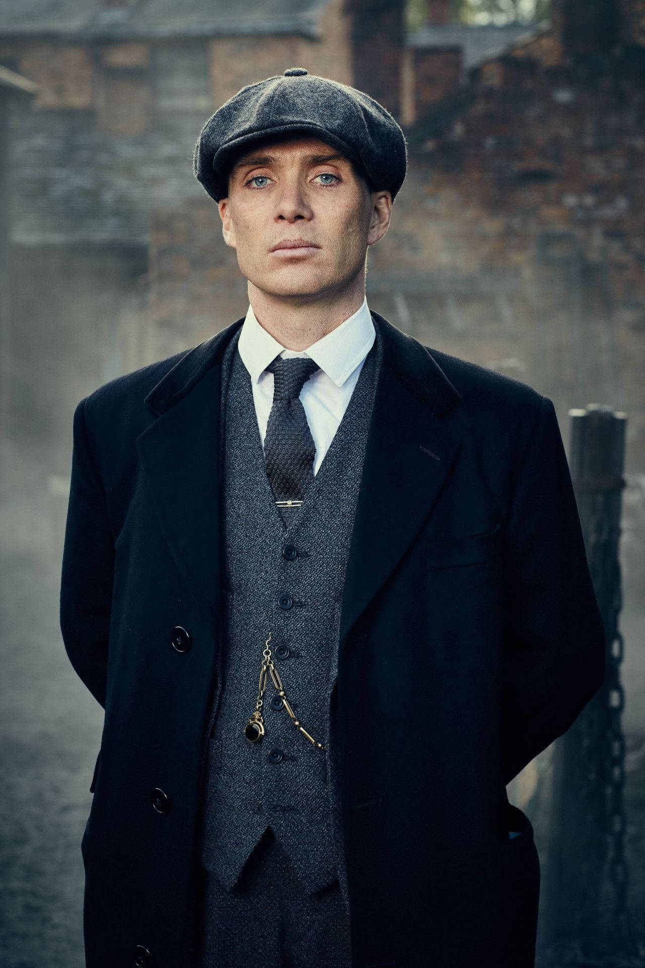 身穿復古西裝和帽子的男子站在霧氣瀰漫的城市小巷中。 — Peaky Blinders 壁紙