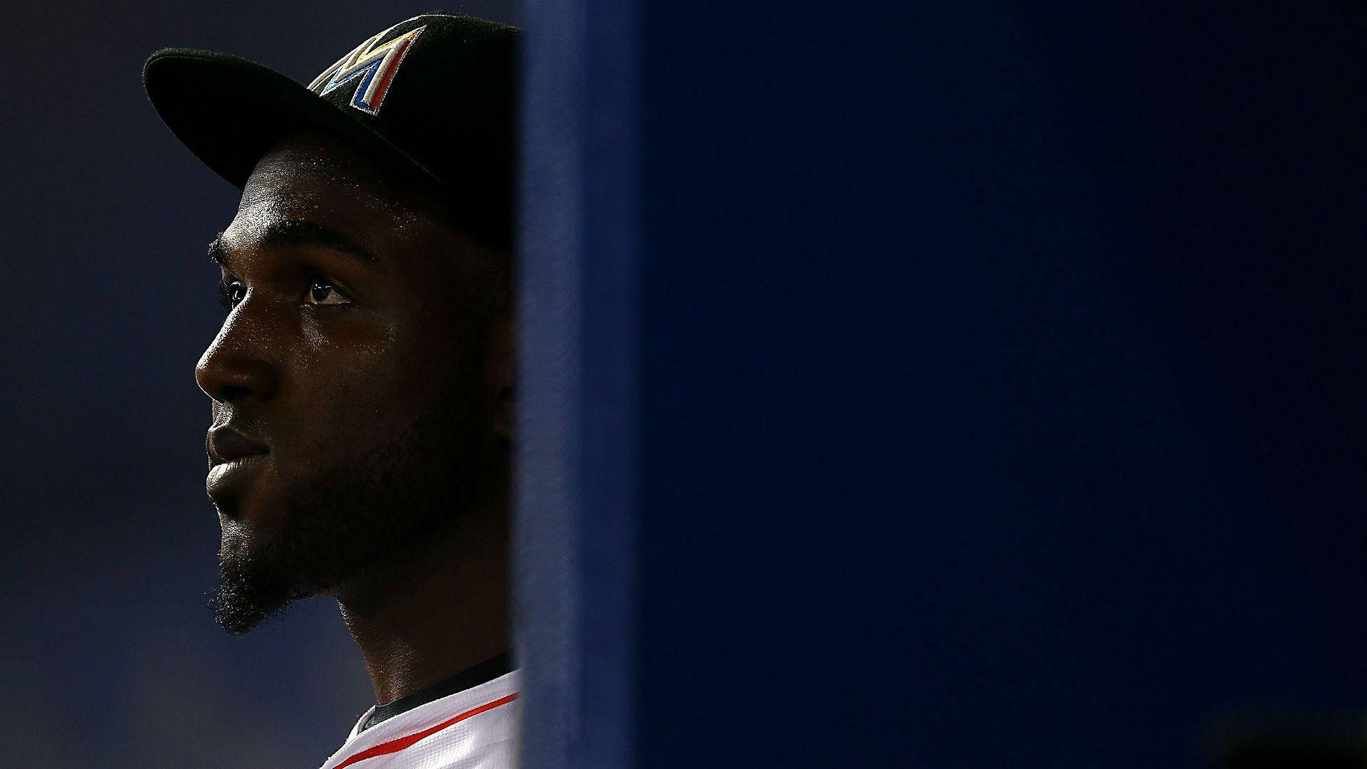 MLB 桌布 壁紙 — 一名戴著棒球帽的球員在球場燈光下，從藍色屏障後若有所思地凝視。