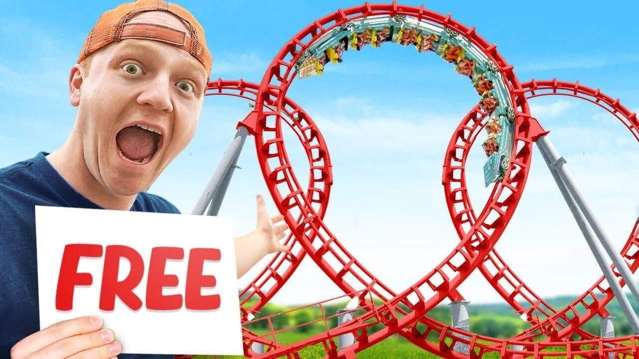 Free 桌布 壁紙 — 一名戴著橘色帽子的男子，在紅色雲霄飛車前舉著「免費」的牌子，雲霄飛車上的乘客在空中繞圈。