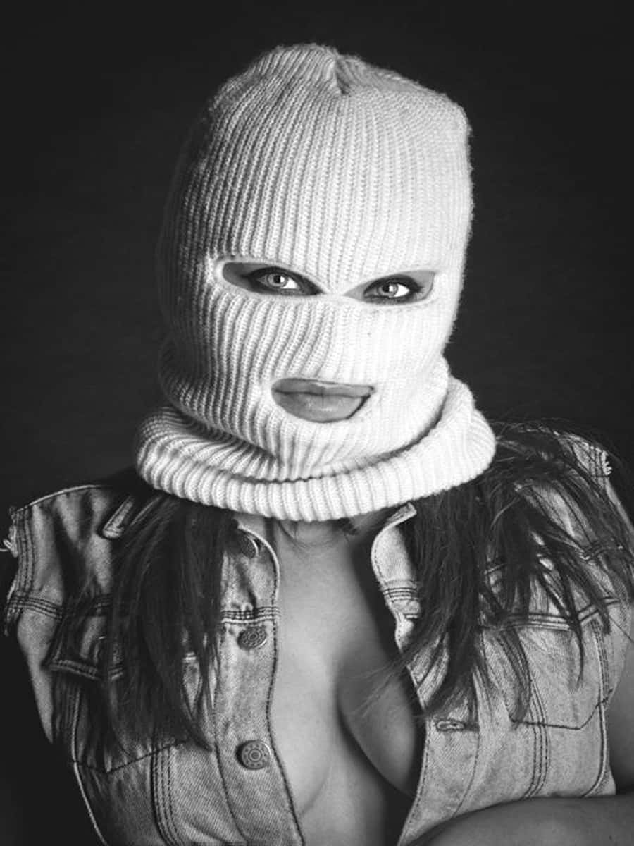 Ski Mask Girl 桌布 壁紙 — 一名戴著白色針織巴拉克拉法帽的女子，在黑色背景下用深色眼睛強烈凝視。