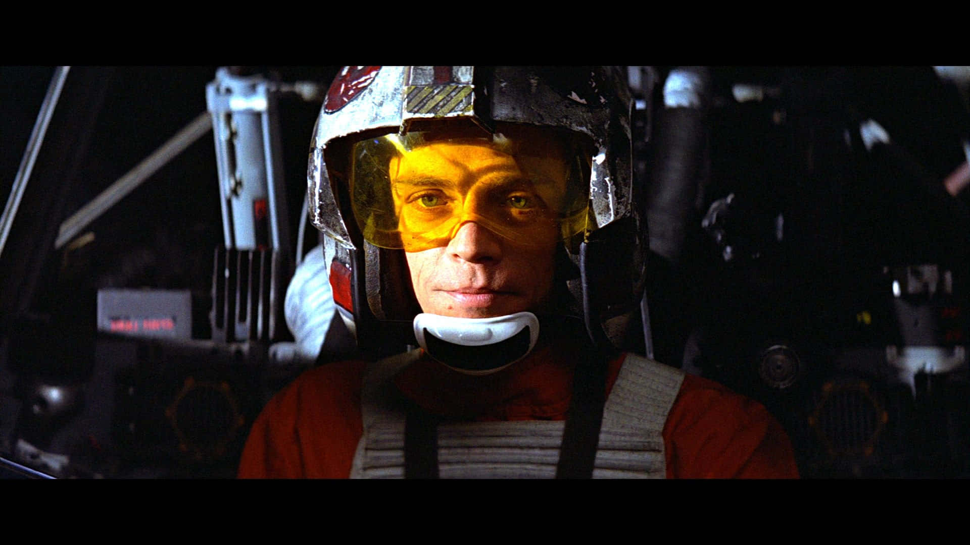 Return Of The Jedi 桌布 壁紙 — 一名戴著磨損頭盔、黃色面罩的飛行員，在充滿發光控制裝置的昏暗駕駛艙內凝視著。