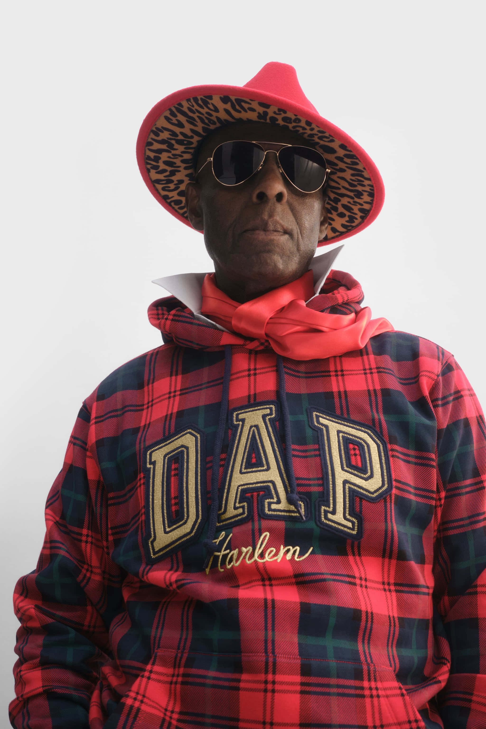 Hoodie 桌布 壁紙 — 一名戴著紅色豹紋帽和太陽眼鏡的男子，身穿一件大膽的紅色格子連帽衫，胸前繡有「DAP Harlem」字樣。