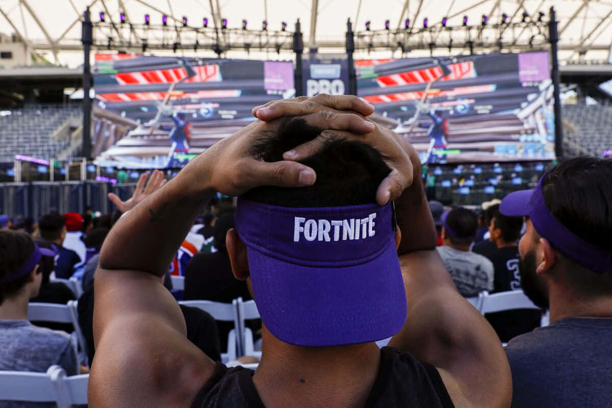 Gaming Conventions 桌布 壁紙 — 一名戴著紫色Fortnite帽子的粉絲在電競錦標賽場地沮喪地抱著頭。