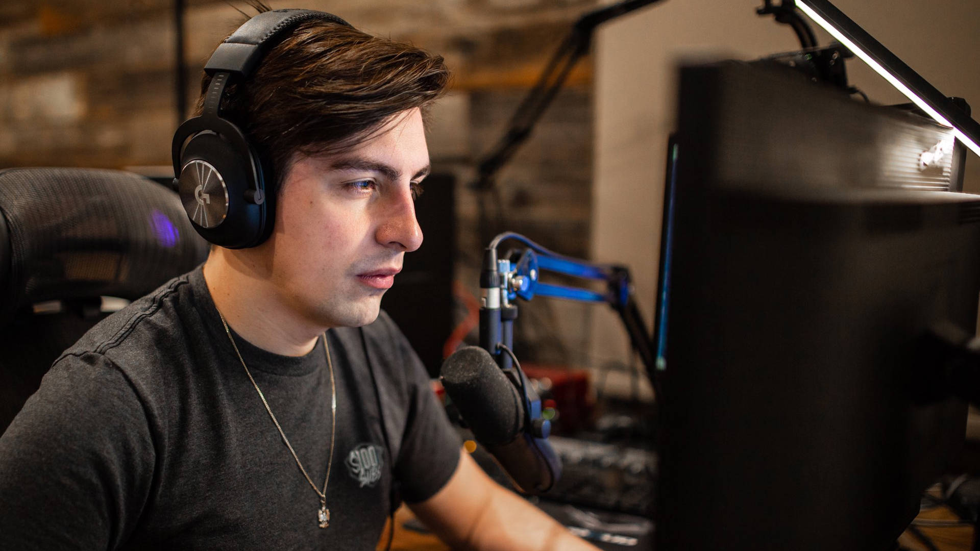 Shroud 桌布 壁紙 — 一名戴著耳機的年輕男子在昏暗的燈光下，專注地看著電腦螢幕，旁邊有麥克風和LED燈光。