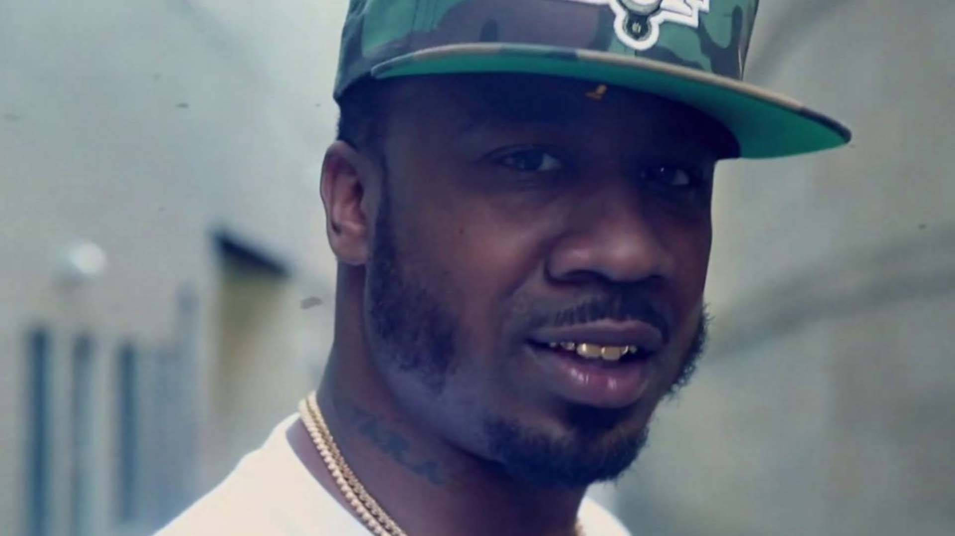 屠夫班尼 桌布 壁紙 — 一名戴著迷彩帽和金鏈的男子近距離肖像，表情嚴肅。