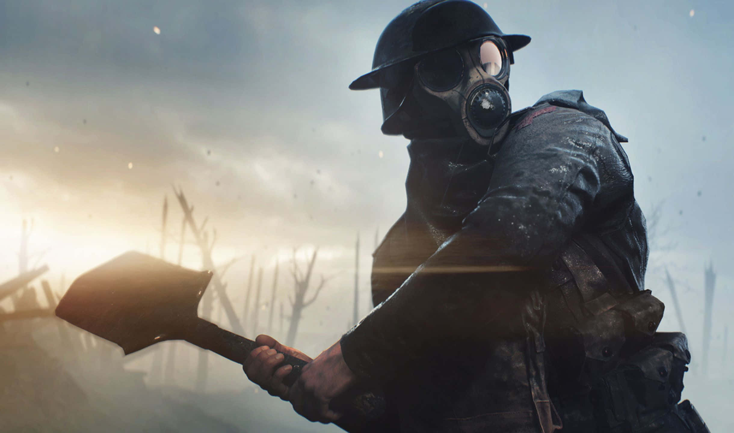 2440x1440 Battlefield 1 桌布 壁紙 — 一名戴著防毒面具和頭盔的士兵，在光禿樹木和朦朧陽光的陰沉戰場背景下緊握著鏟子。