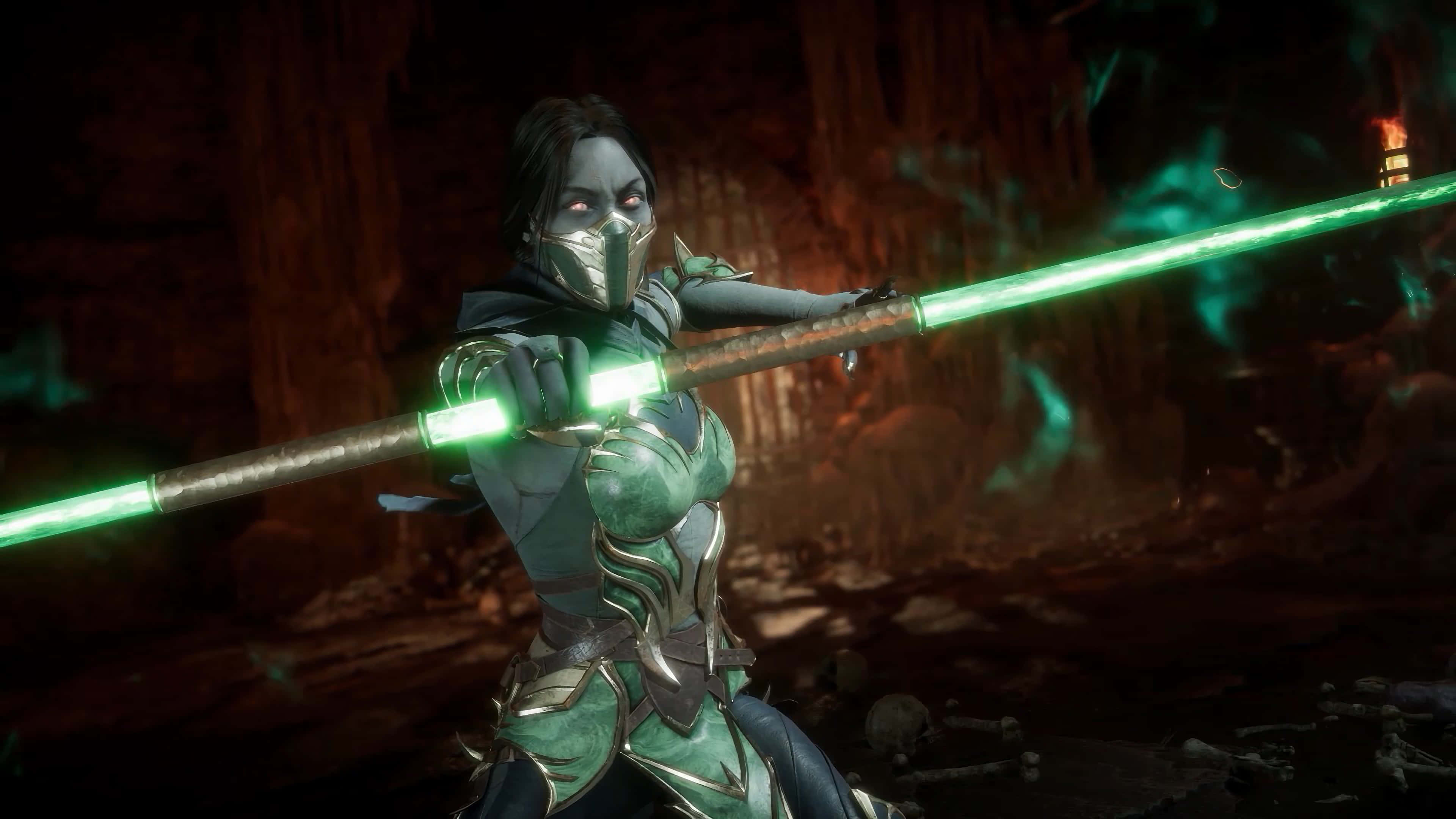 Mortal Kombat Jade 桌布 壁紙 — 一名戴著面具的戰士身穿綠色盔甲，在黑暗的洞穴廢墟中揮舞著發光的綠色法杖。