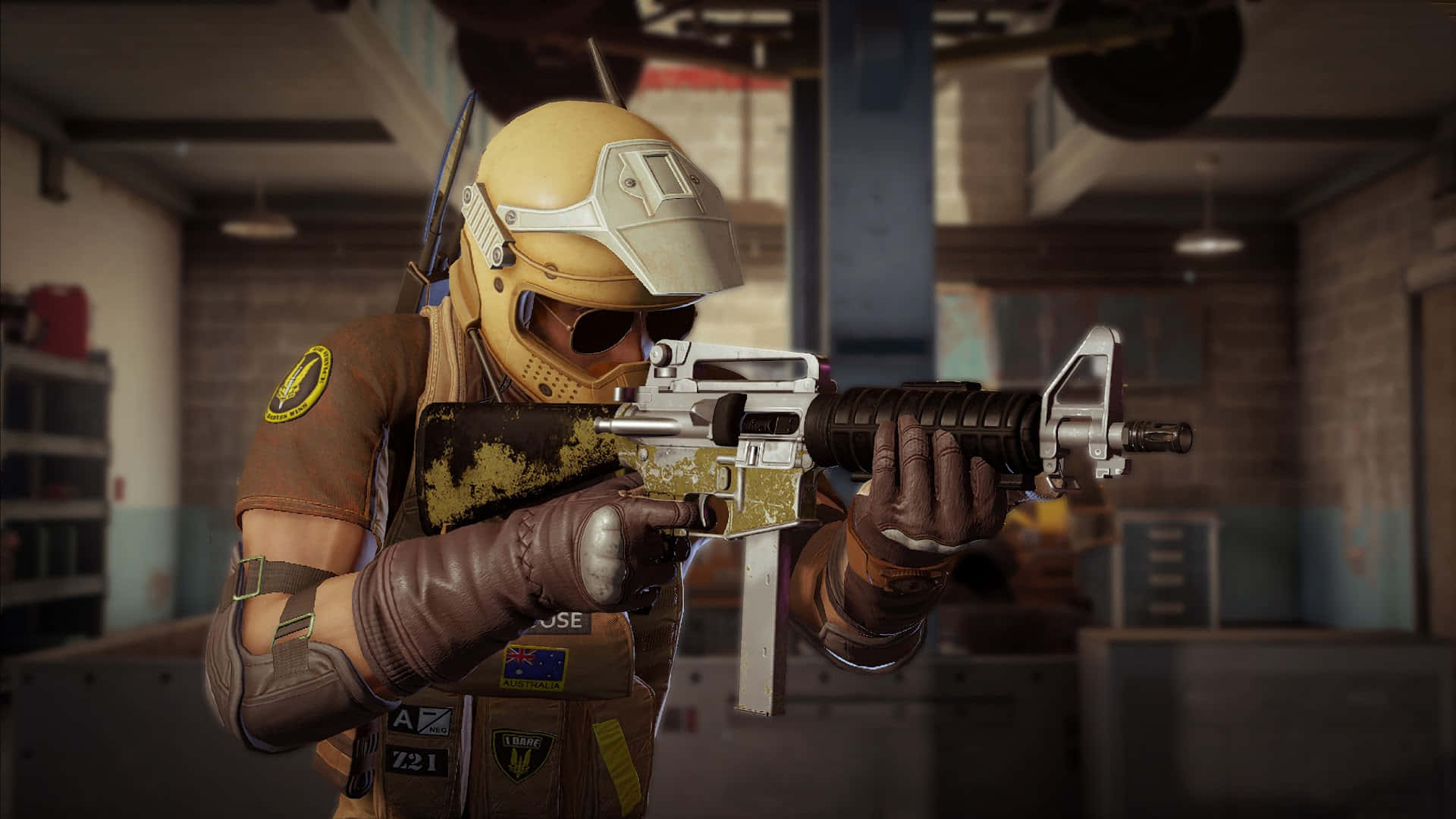 Rainbow Six Siege Mozzie 桌布 壁紙 — 一名戴著黃色頭盔、身穿棕色裝備的士兵，在昏暗的工業倉庫內瞄準一支金銀色的突擊步槍。