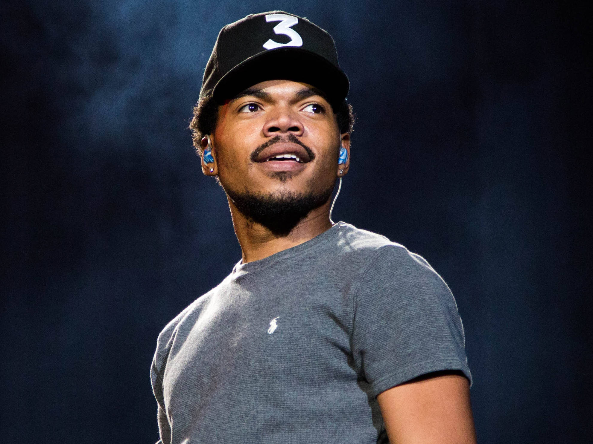 chance 桌布 壁紙 — 一名戴著黑色帽子、上面有白色數字三和藍色耳機的男子，在黑暗煙霧背景中表情豐富地向上望。