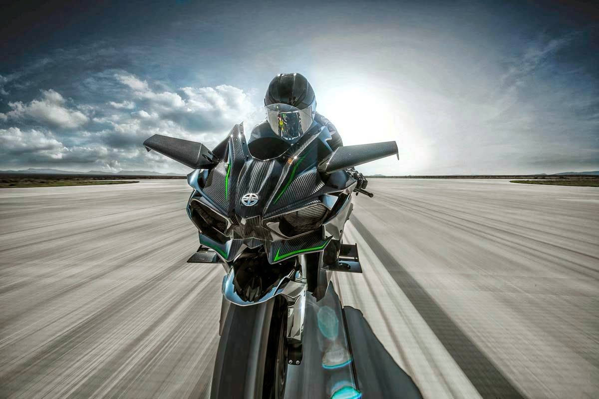 Racing 桌布 壁紙 — 一名戴著黑色頭盔的騎士，在戲劇性的多雲天空下，騎著時尚的黑色和綠色摩托車，在廣闊的沙漠跑道上向鏡頭飛馳。