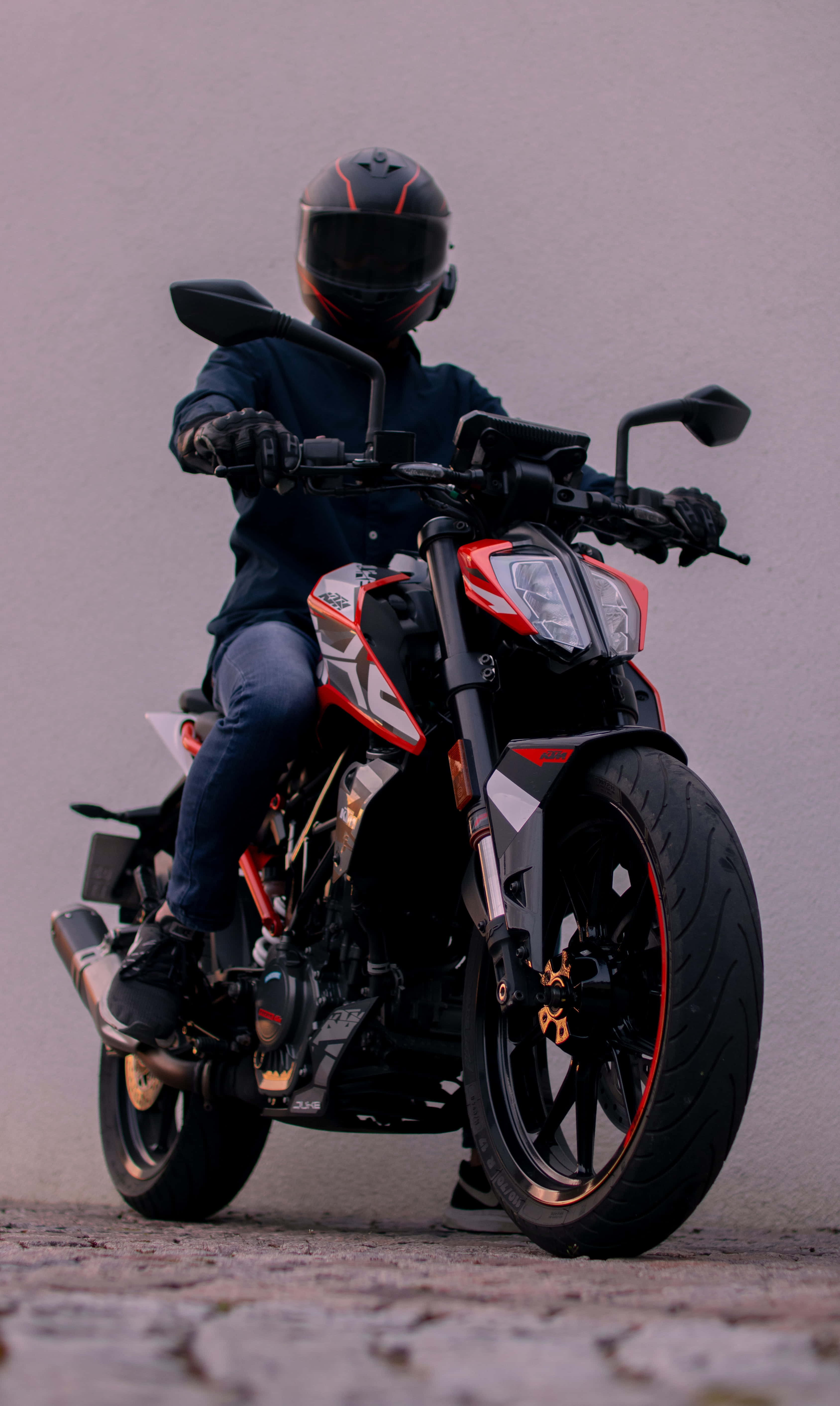 Helmet 桌布 壁紙 — 一名戴著黑色頭盔的騎士坐在紅色和黑色的運動摩托車上，背景是柔和的灰色。