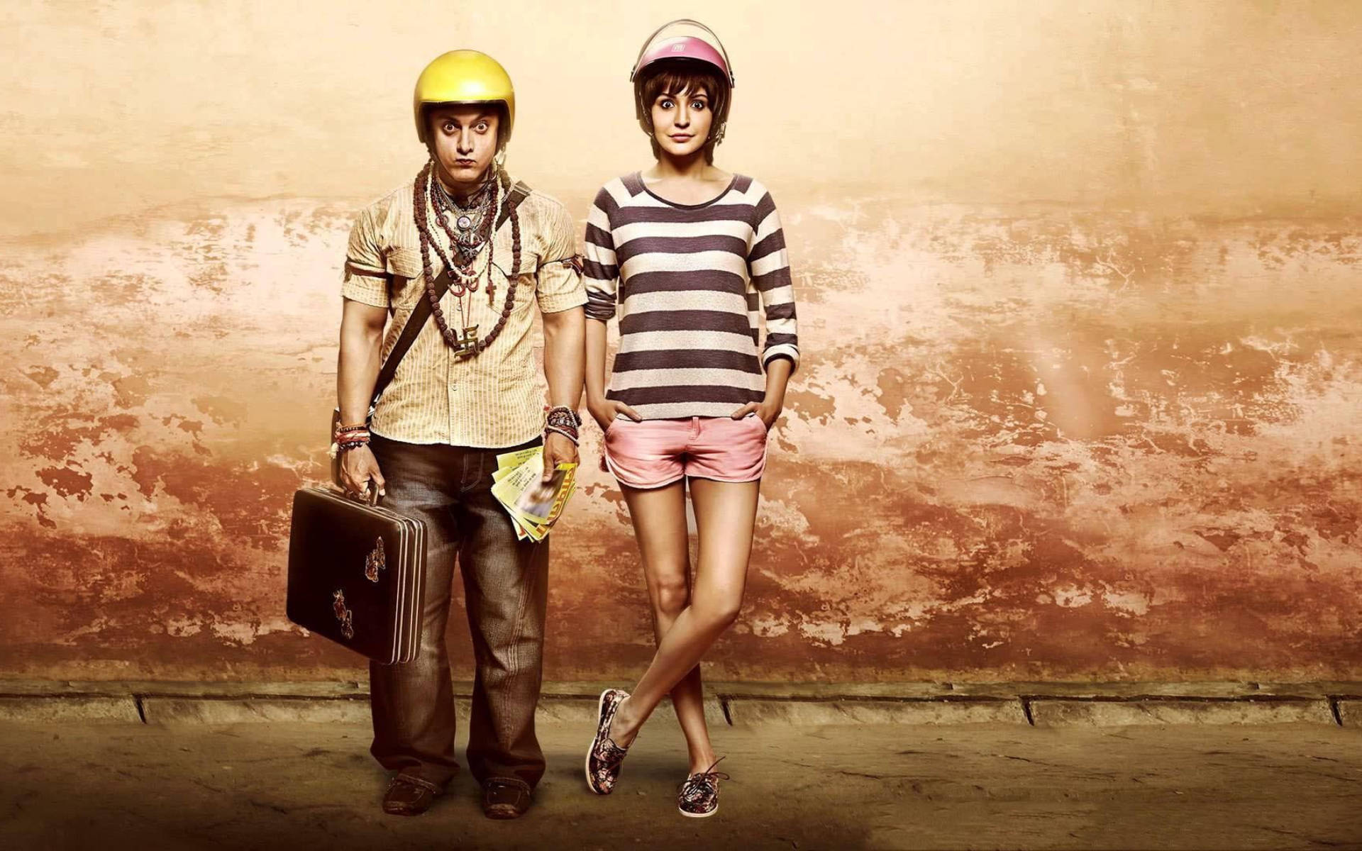 Aamir Khan 桌布 壁紙 — 一名戴頭盔的男人和女人站在風化的牆前，他提著一個手提箱，她穿著粉紅色短褲。