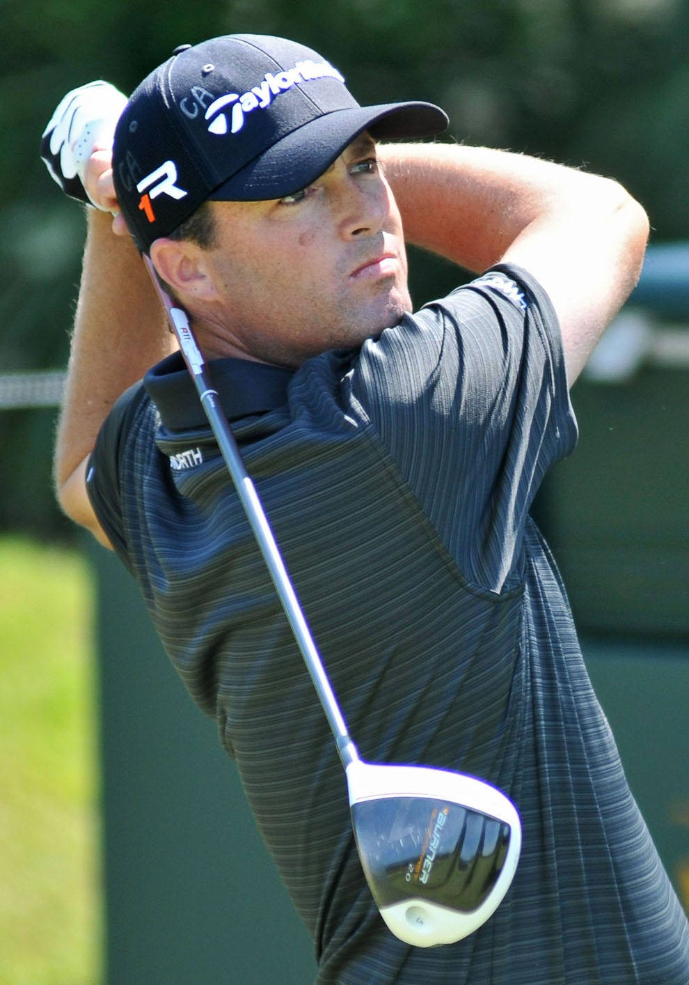 Ryan Palmer 桌布 壁紙 — 一名戴黑色帽子和條紋襯衫的男性高爾夫球手在陽光明媚的高爾夫球場上用一號木桿執行強力揮桿。