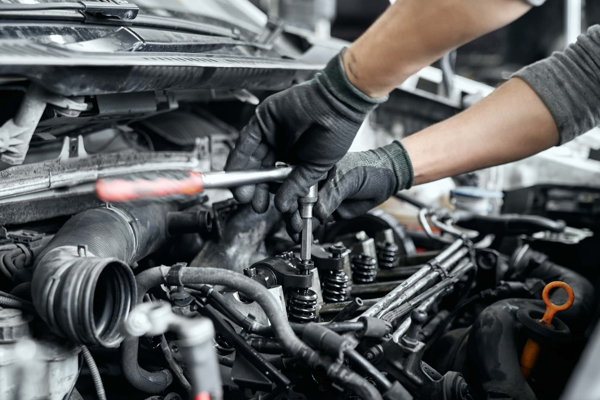 Mechanic 桌布 壁紙 — 一名戴黑色手套的技工在引擎蓋下用扳手鎖緊汽車引擎上的螺栓。
