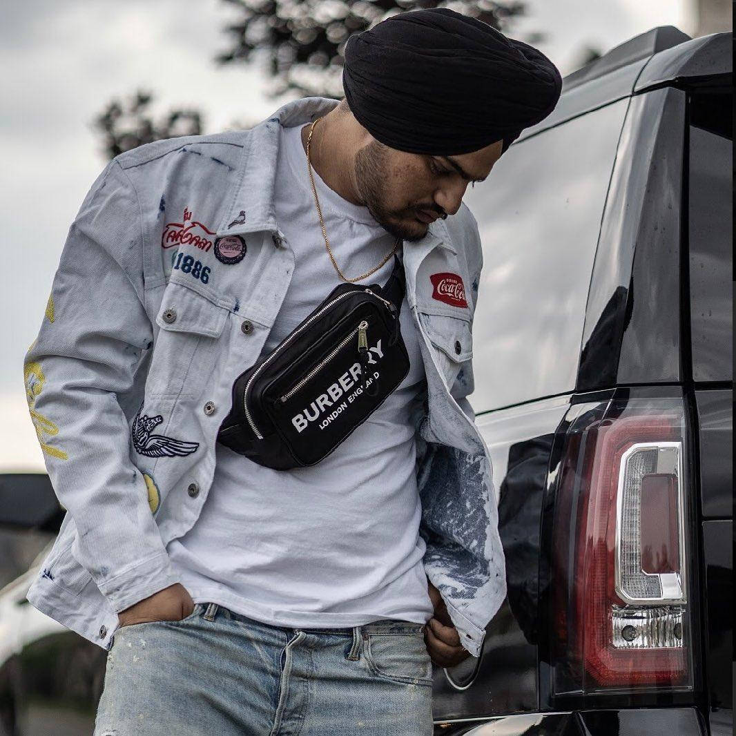 戴頭巾和牛仔外套的男子靠著黑色SUV，配有腰包。 — Sidhu Moose Wala 壁紙