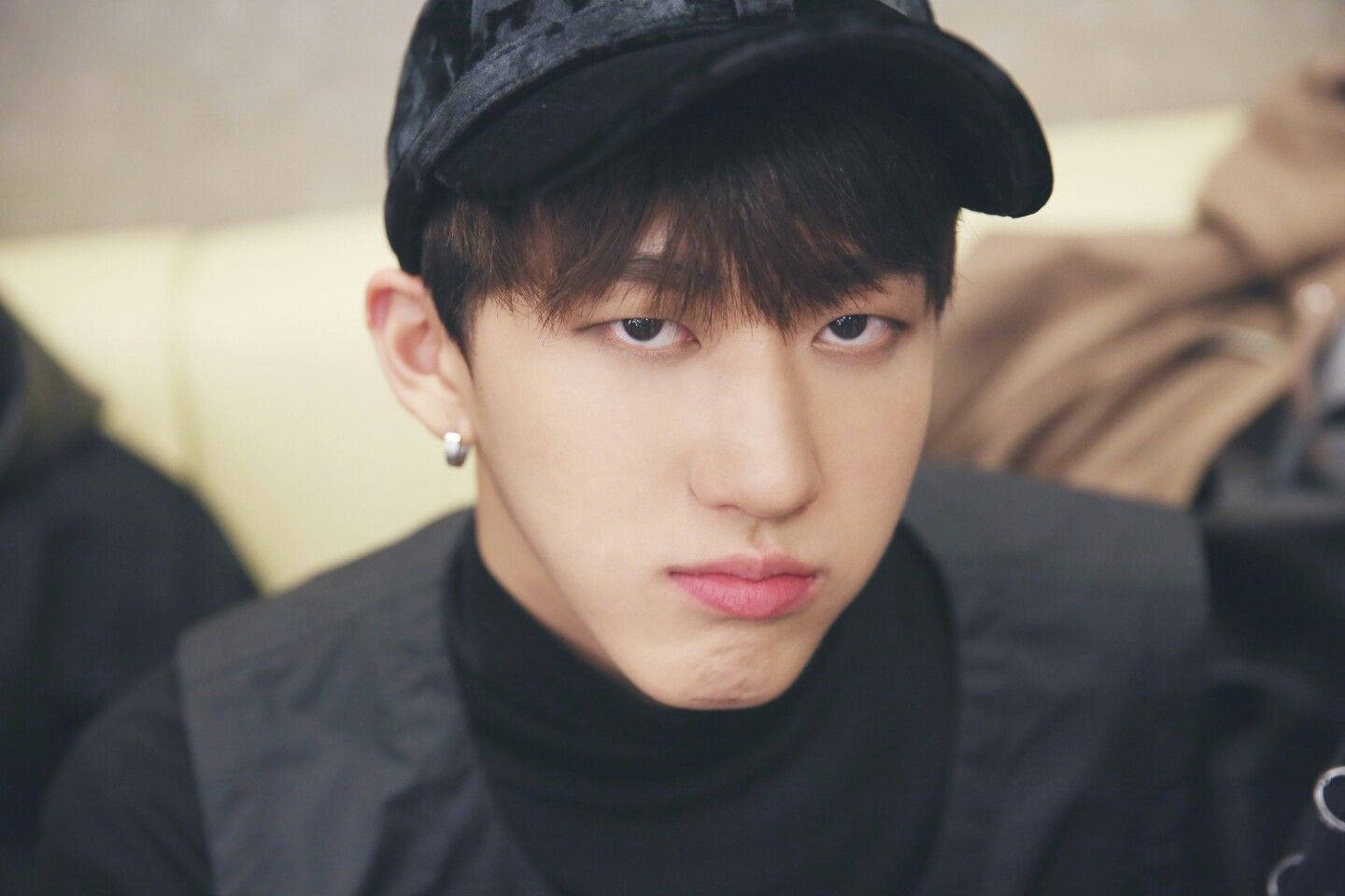 Changbin 桌布 壁紙 — 一名戴黑色鴨舌帽和高領毛衣的年輕男子，表情嚴肅地凝視著相機。