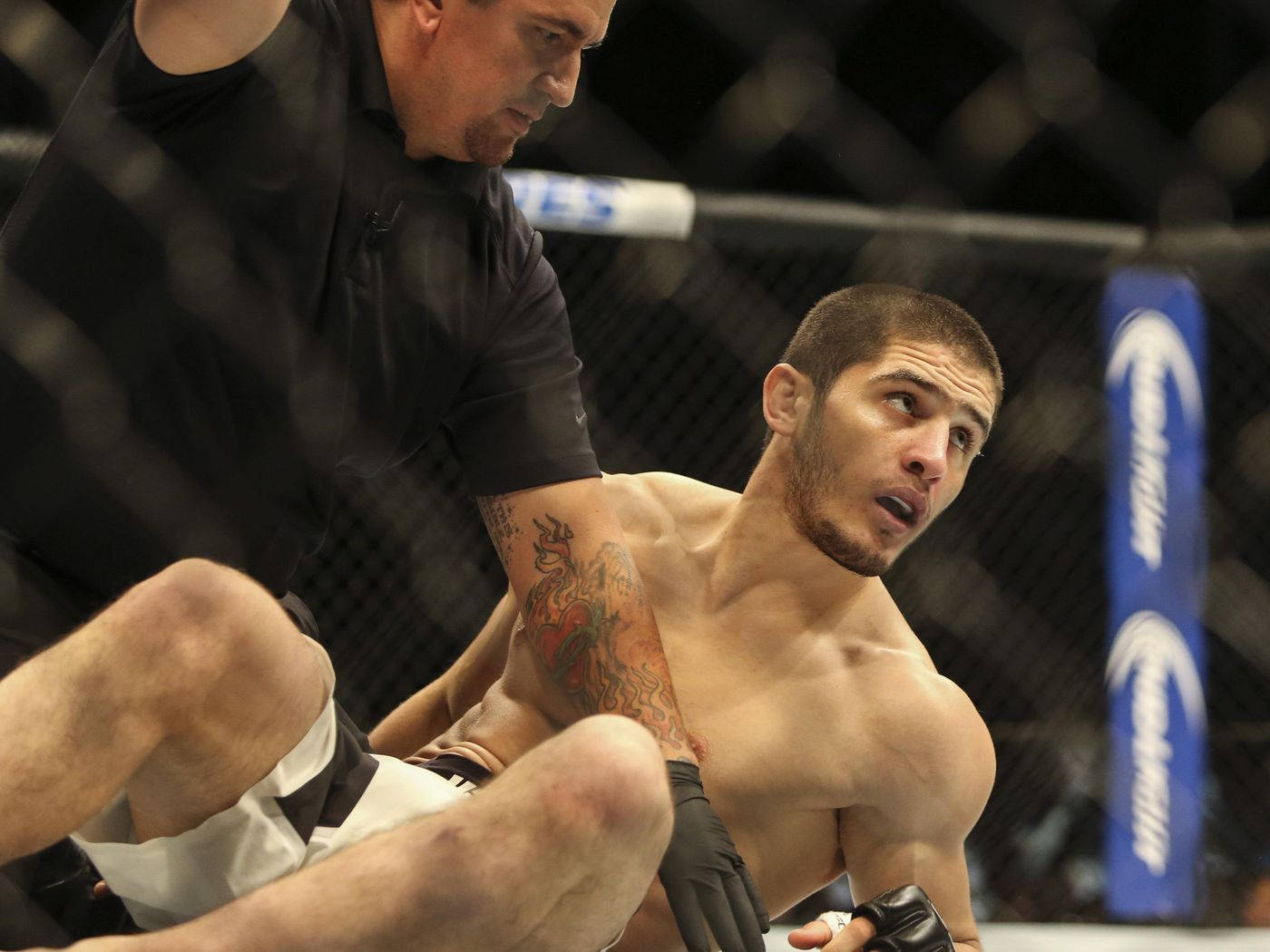 UFC 桌布 壁紙 — 一名手臂有刺青的拳手在MMA八角籠比賽中被裁判阻止。
