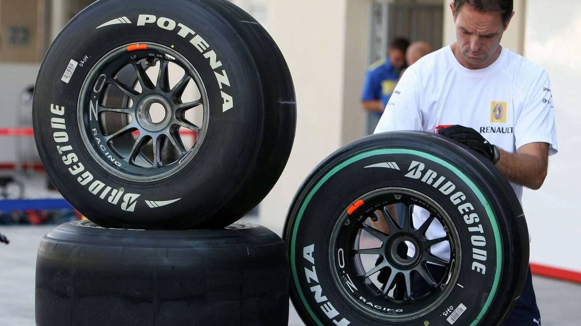 標誌 桌布 壁紙 — 一名技師正在處理一條Bridgestone Potenza賽車輪胎，而另一條則放在維修區車庫的輪胎堆上。