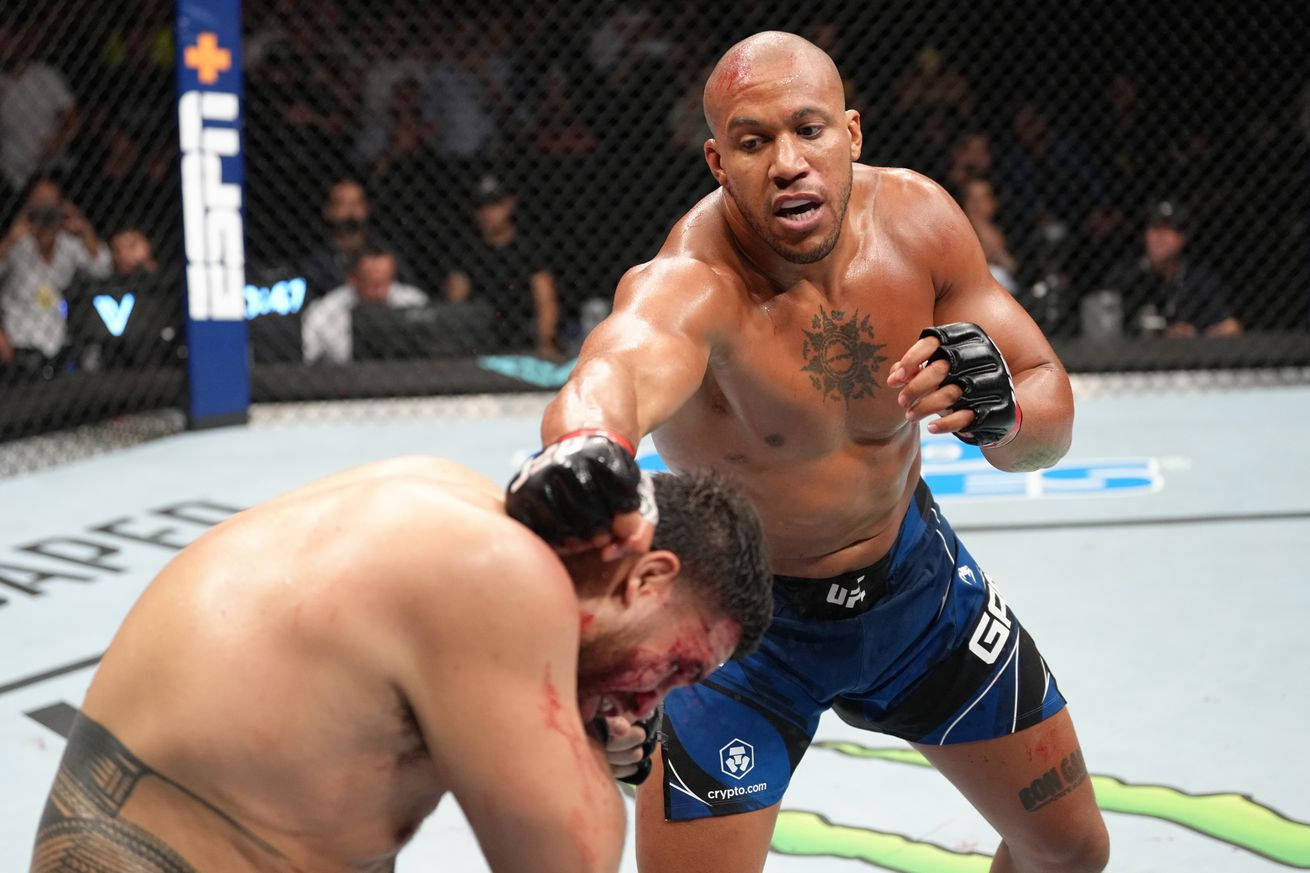 MMA 桌布 壁紙 — 一名拳手在UFC八角籠中向對手打出強力一拳，兩人身上都可見血跡。