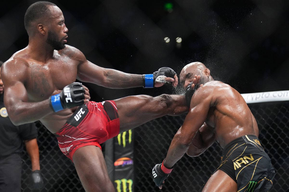 MMA 桌布 壁紙 — 一名拳手在UFC八角籠中向對手施展強力高踢，汗水在明亮的場館燈光下飛濺。