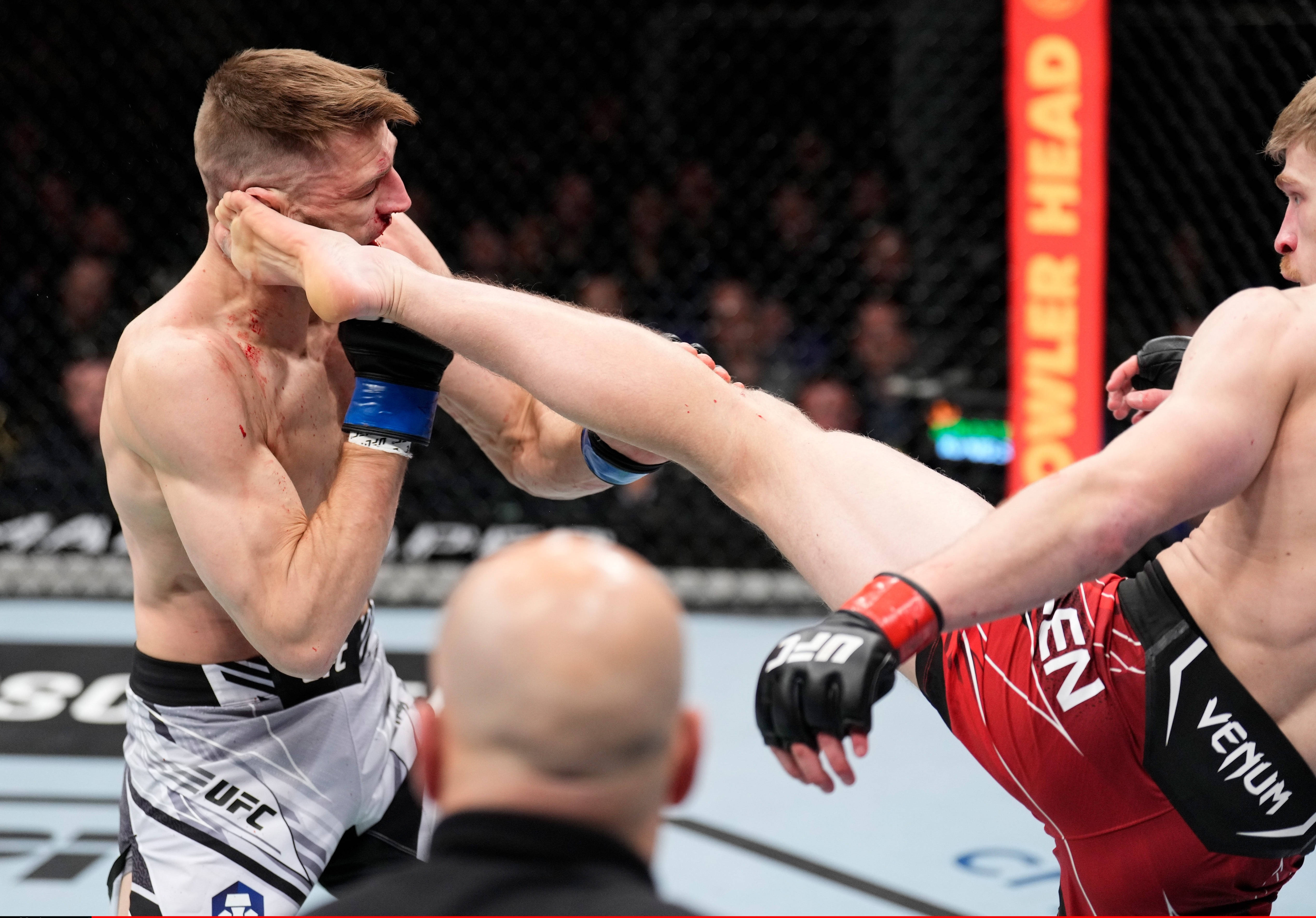 UFC 桌布 壁紙 — 一名拳手在UFC八角籠中向對手面部踢出高踢，臉頰上可見血跡。